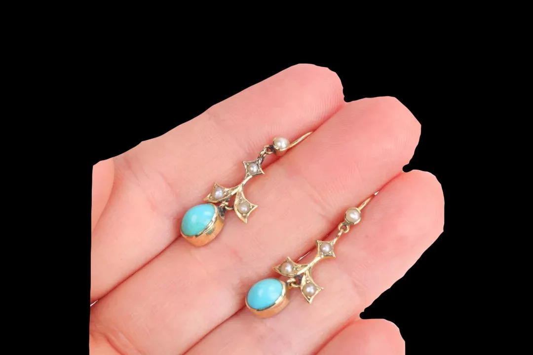 Antique turquoise and split pearl drop earrings resting on fingertips, showing their 31.8 mm length and delicate gold construction.