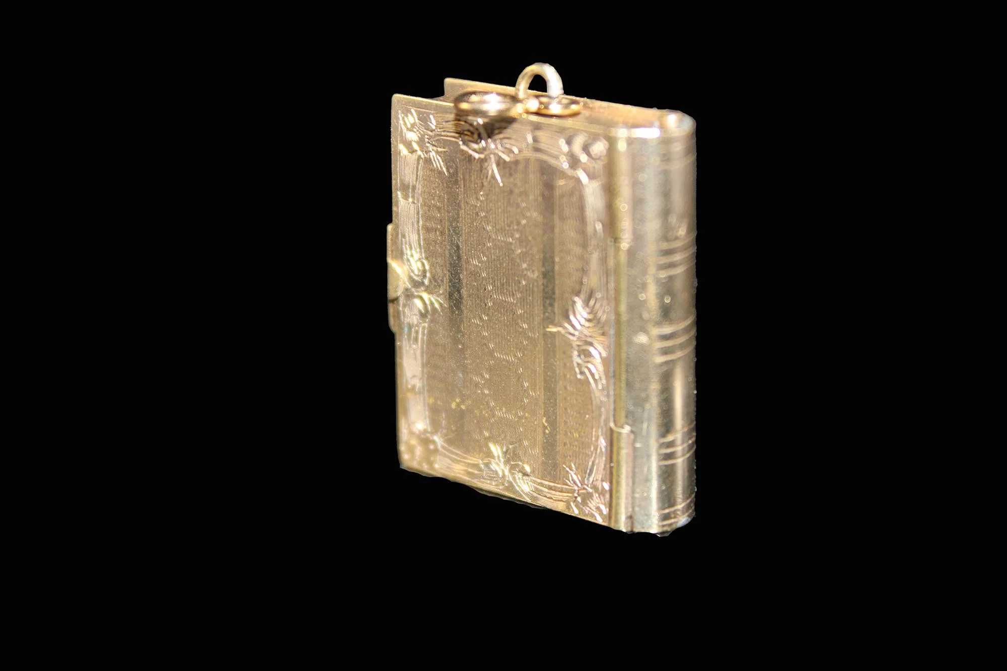 Profile view of antique gold book locket with realistic book spine and page detailing.