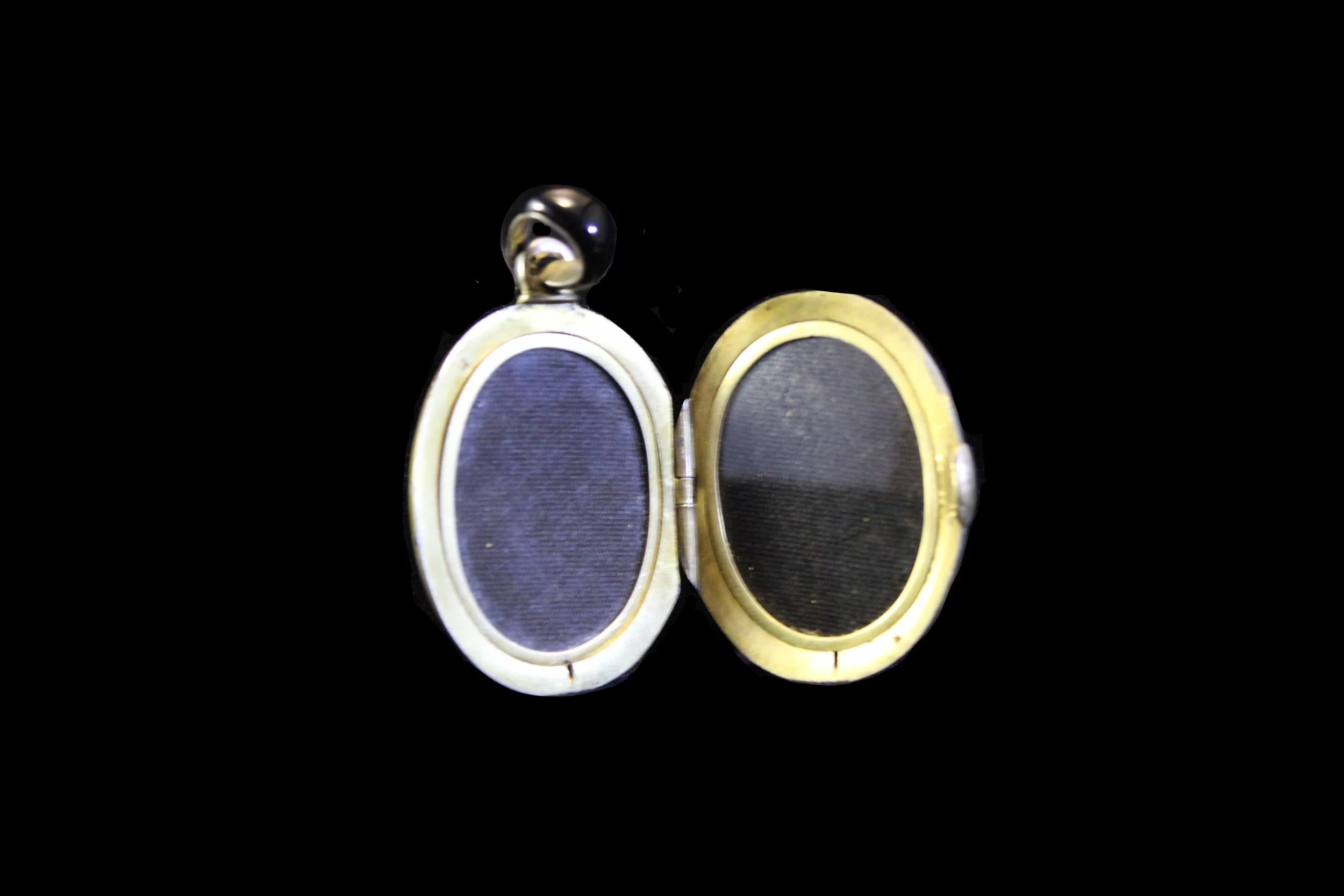 Interior of Victorian enamel locket opened to reveal original fabric-lined compartments