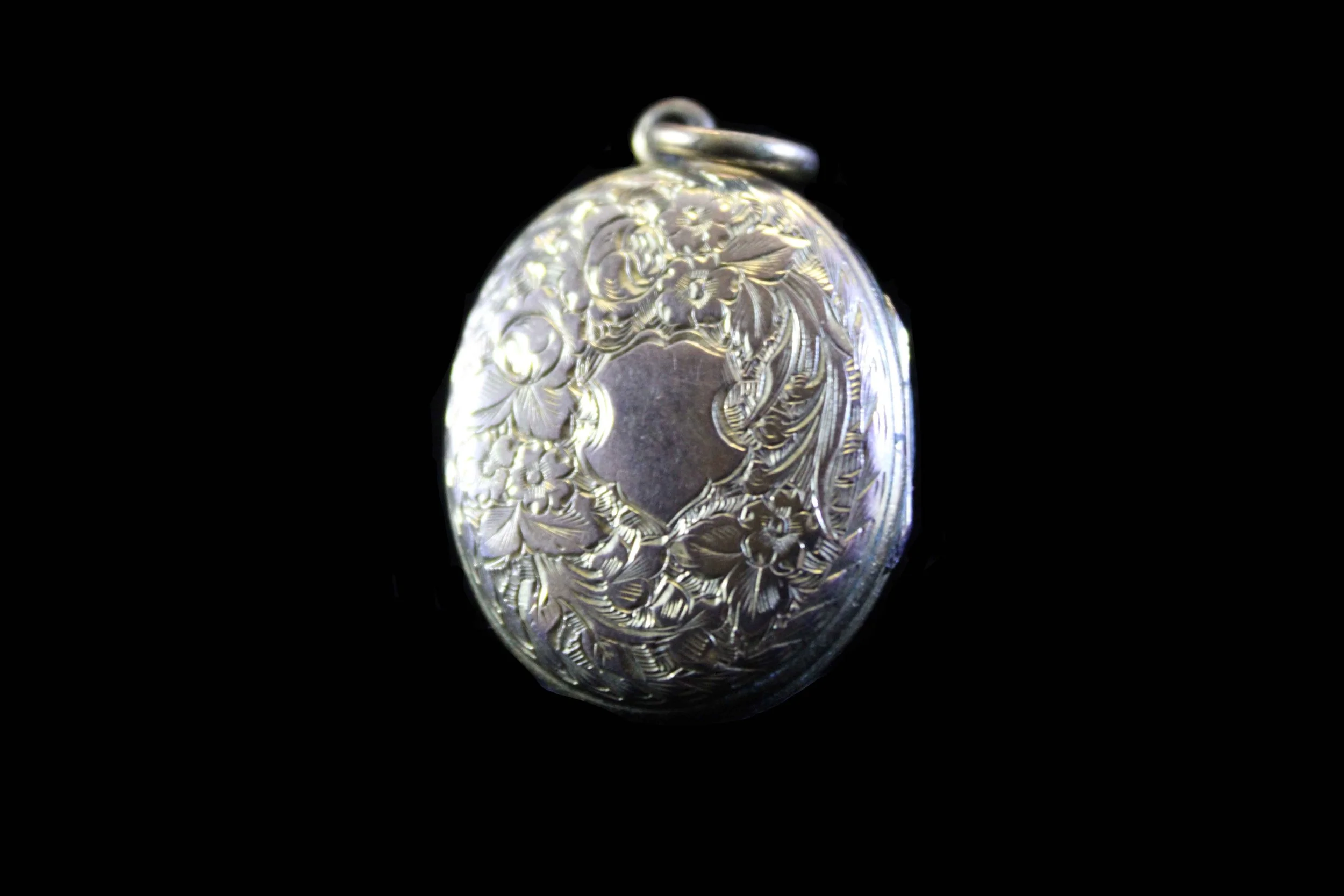 Antique hinged oval locket with repoussé floral engraving and Christian cross, 19th century