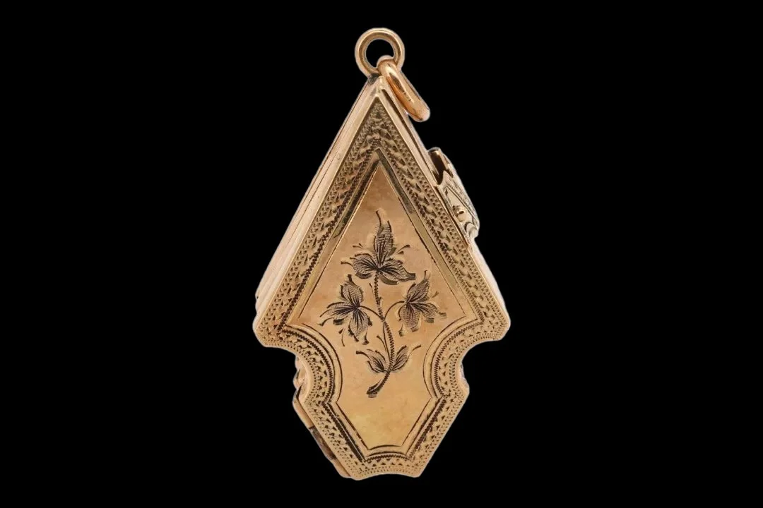 Late Victorian 9ct gold arrow-shaped pendant locket with engraved floral decoration and patterned borders, measuring 3.8 cm when folded.