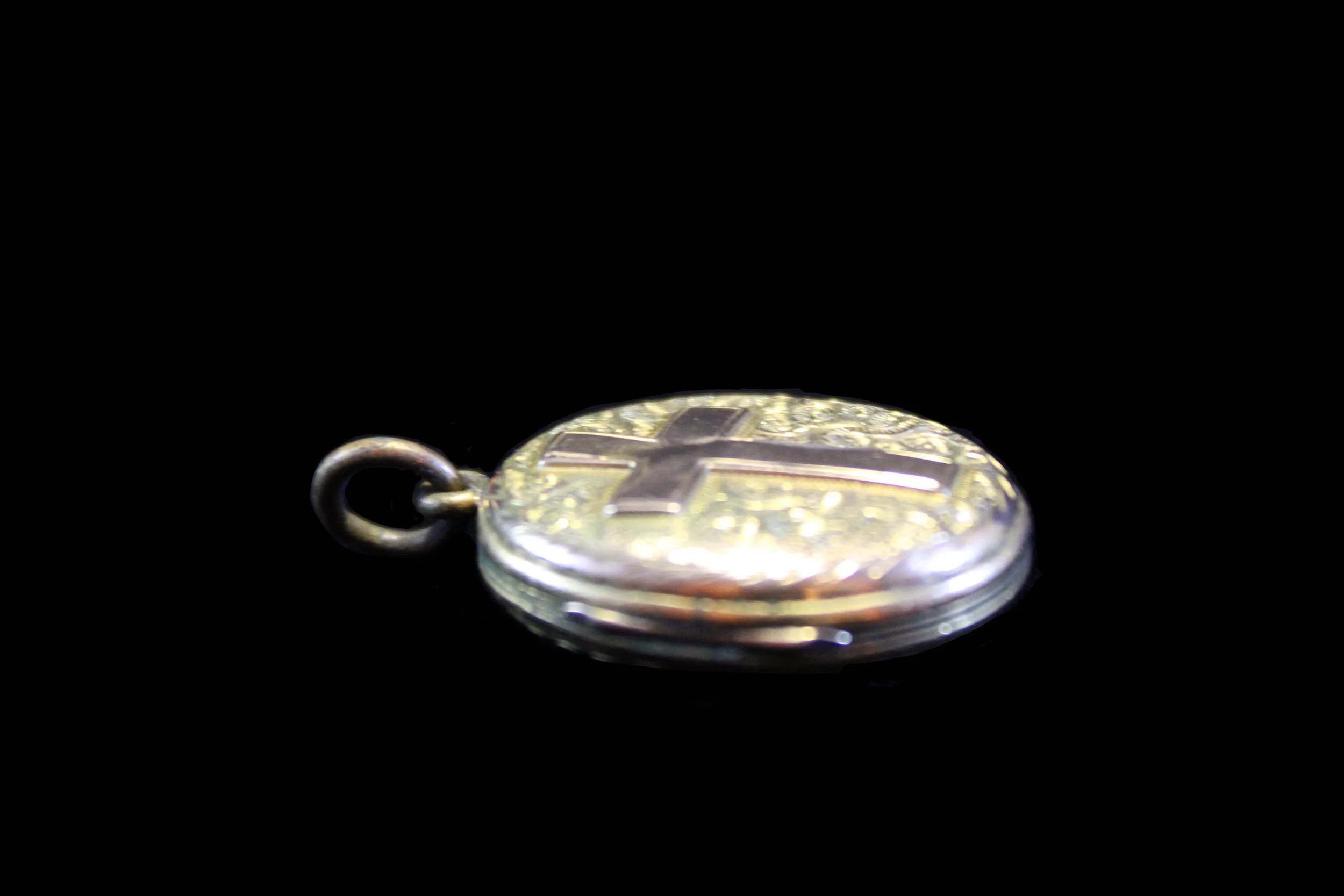 Antique hinged oval locket with repoussé floral engraving and Christian cross, 19th century