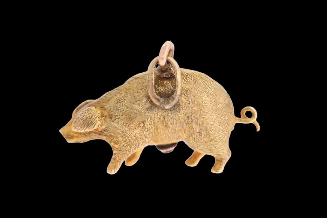 Reverse of antique 9ct gold pig pendant showing naturalistic engraved fur, curled tail, detailed ears and gold suspension loop.