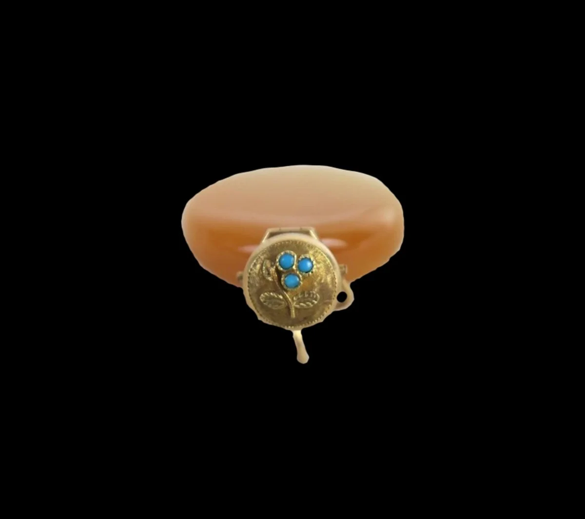 Close-up of antique French gold scent pendant lid featuring three turquoise stones arranged as a flower with engraved leaves.
