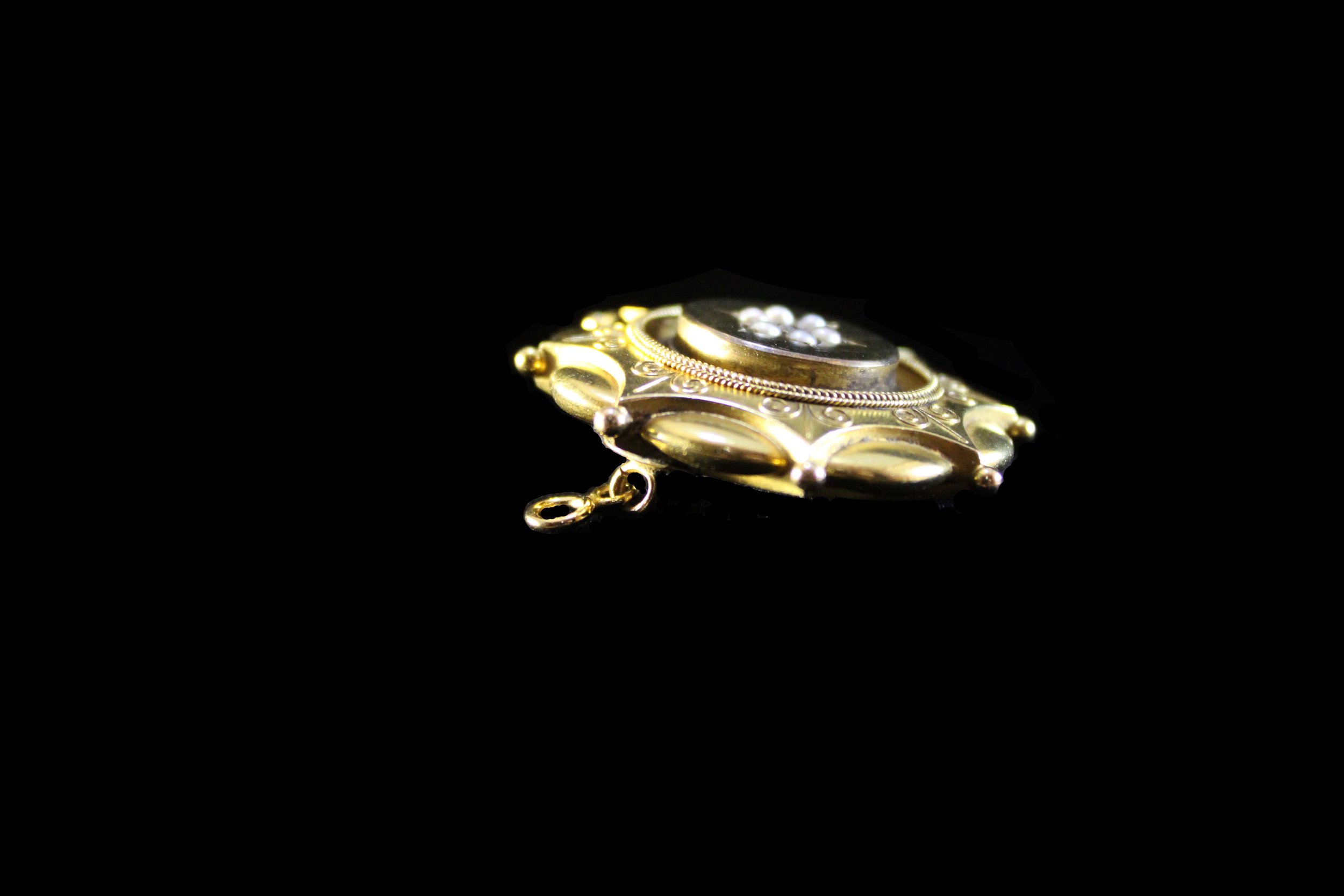 Side profile of Victorian gold mourning pendant with layered construction and applied detailing