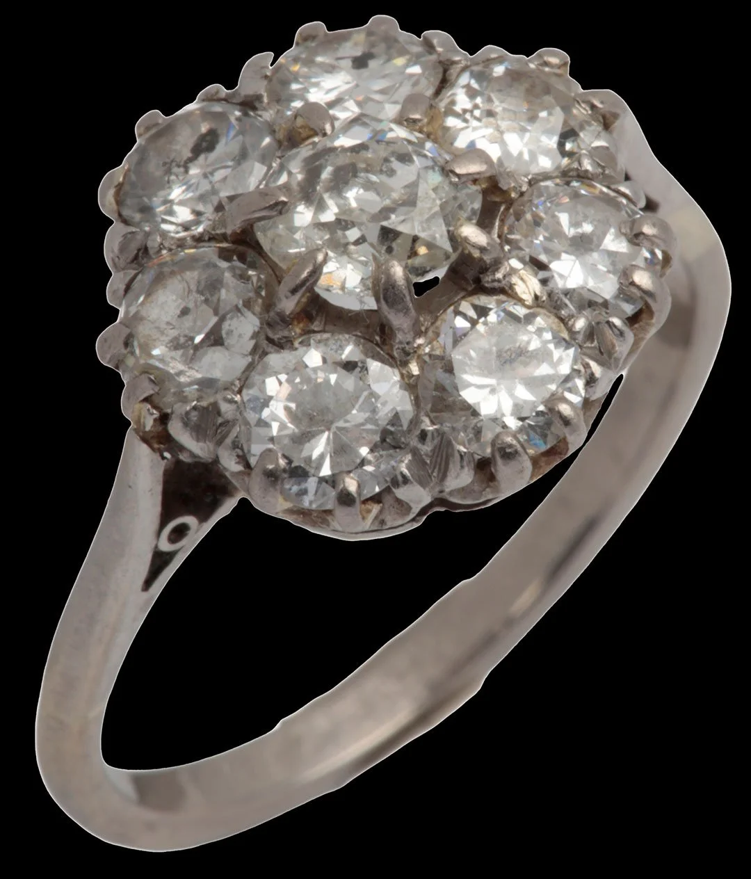 Angled view of antique diamond cluster ring showing eight claw-set diamonds and slender white-gold band.