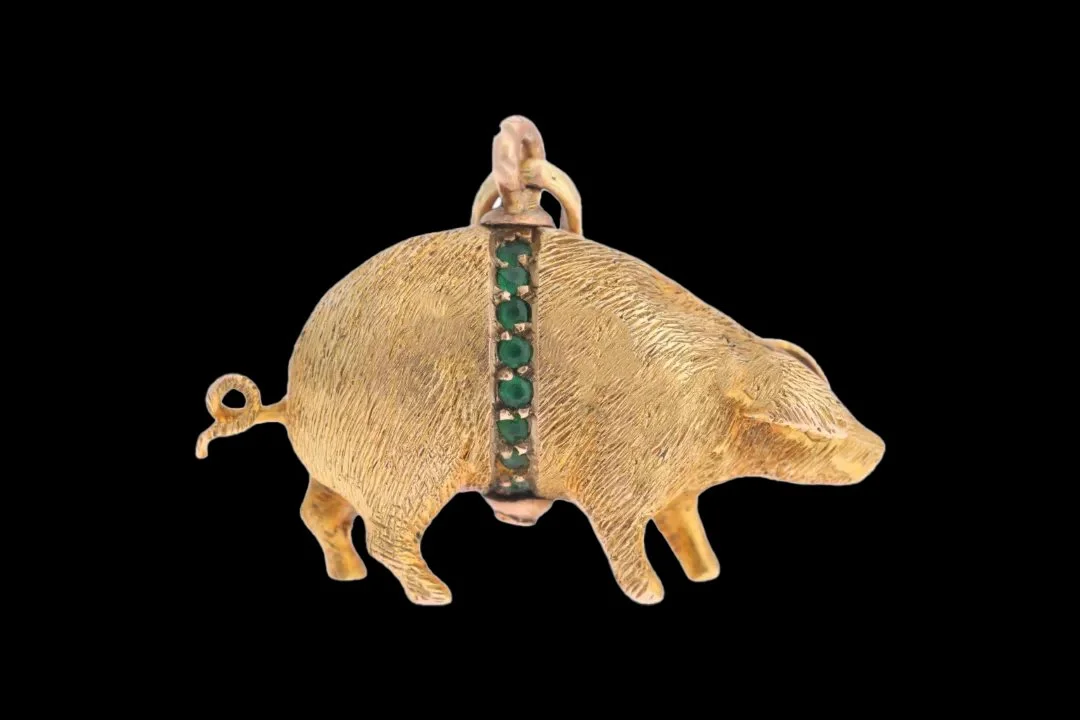 ntique 9ct gold lucky pig charm with textured bristles, curled tail and a band of round-cut green paste stones across its body.