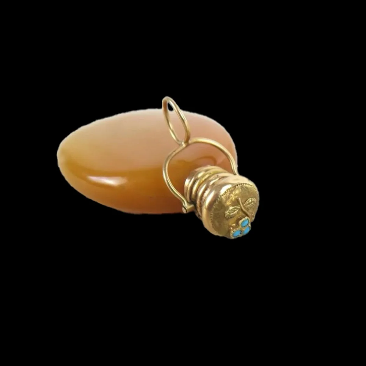 Side view of antique French scent flask showing gold cap decorated with an engraved flower and three turquoise cabochons.