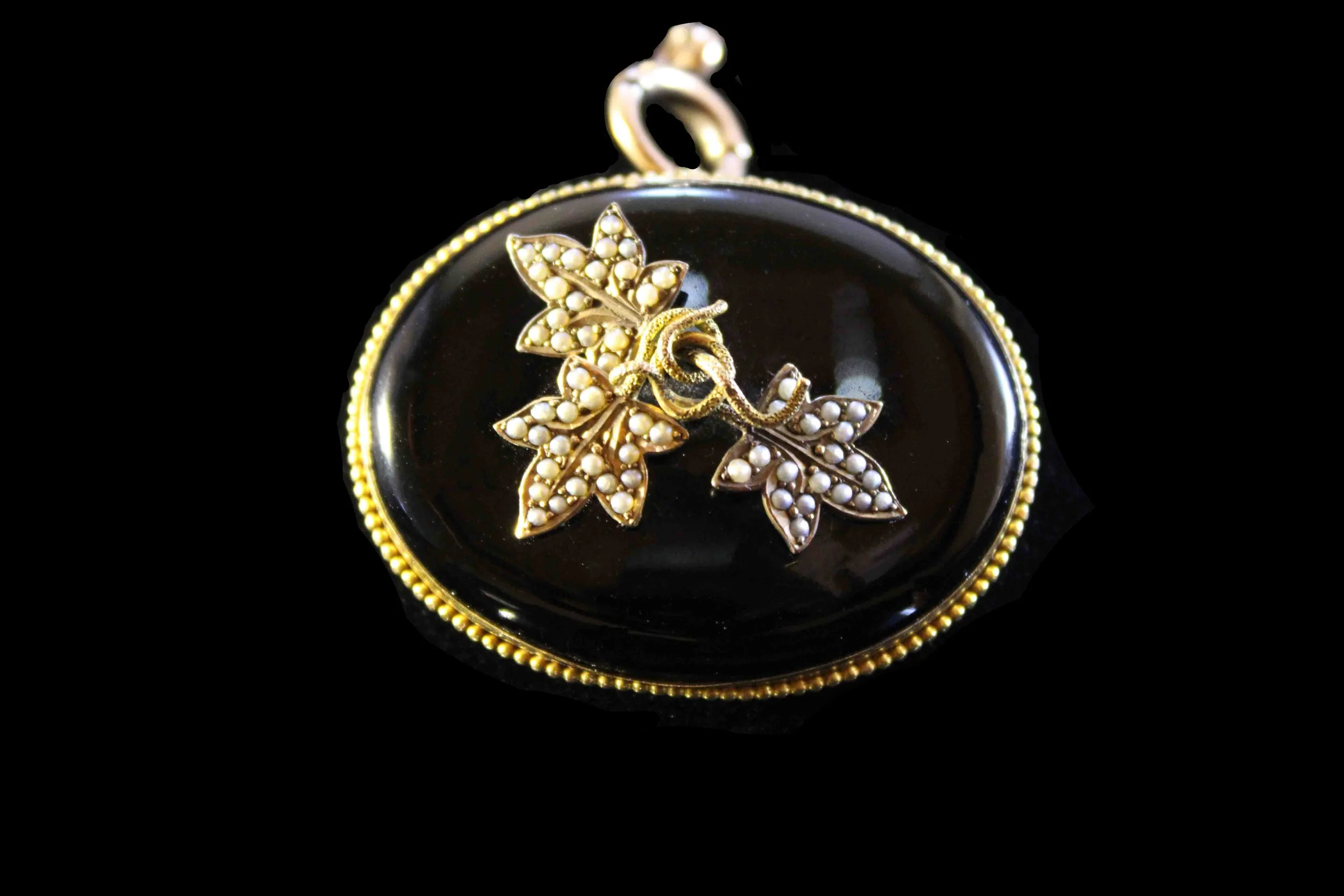 Front view of Victorian mourning locket showing three foliate seed-pearl decorations