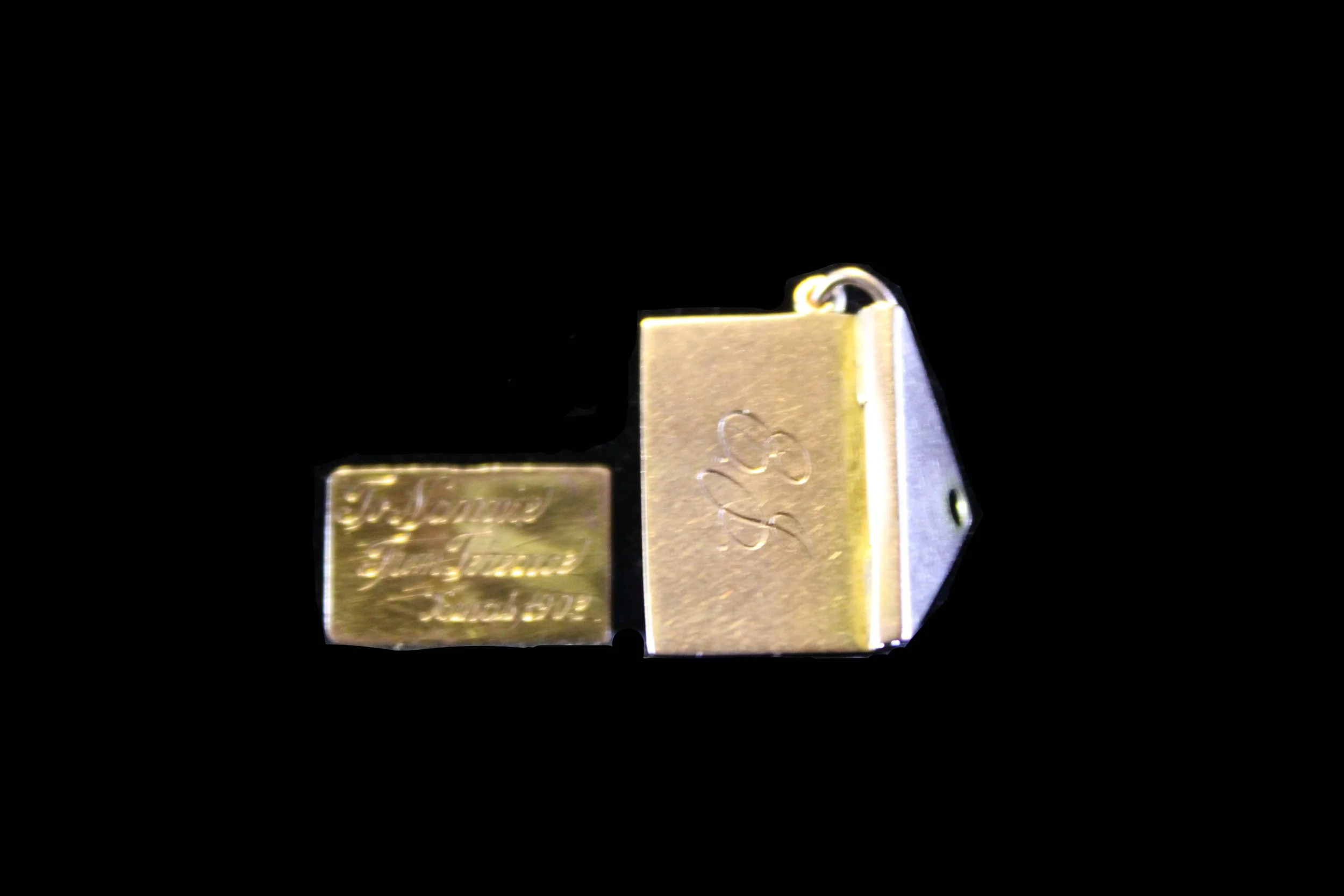 Back of Victorian gold envelope locket engraved with initials, black velvet background