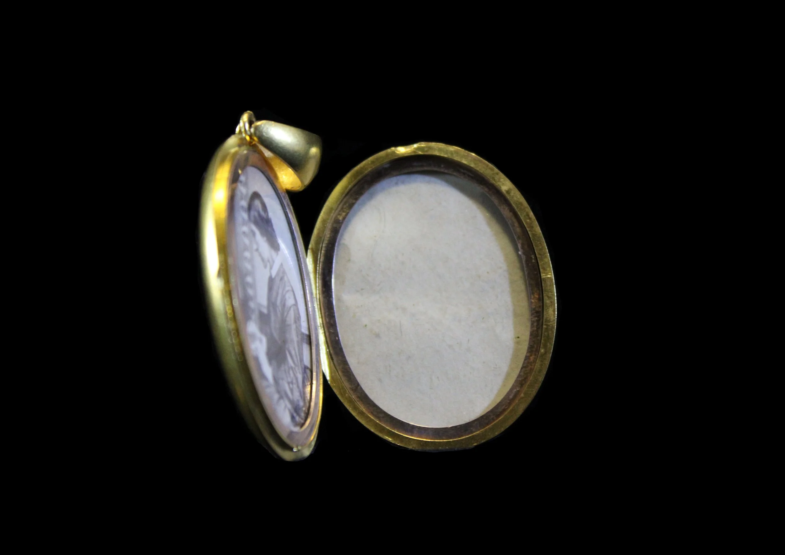 Open antique Victorian gold locket showing original inner compartment with protective cover, black background