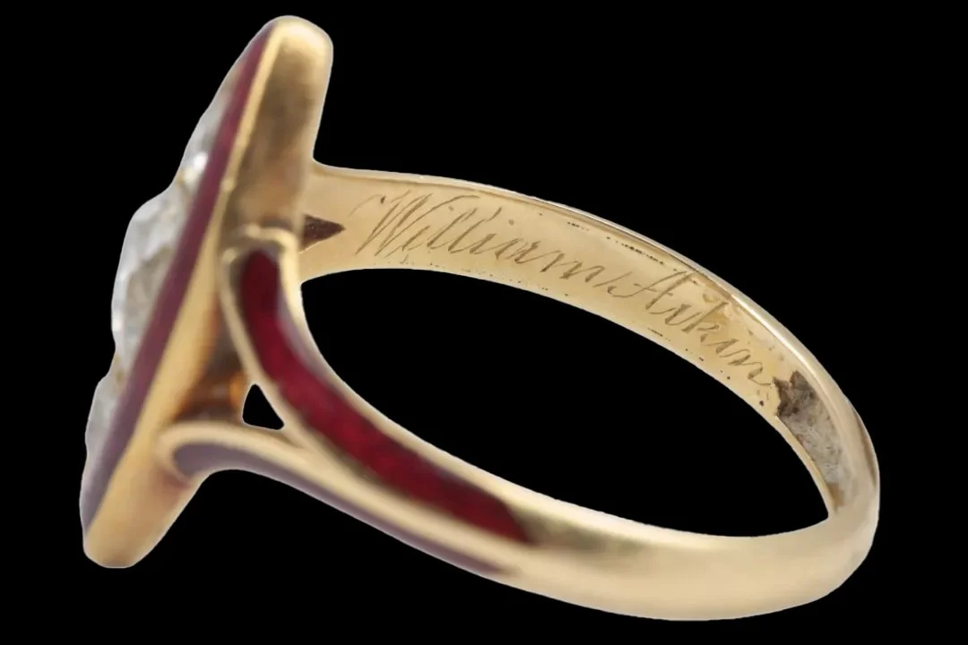 Interior of Victorian gold mourning ring showing hand-engraved memorial inscription commemorating William Aikin, with red enamel on the shoulder.