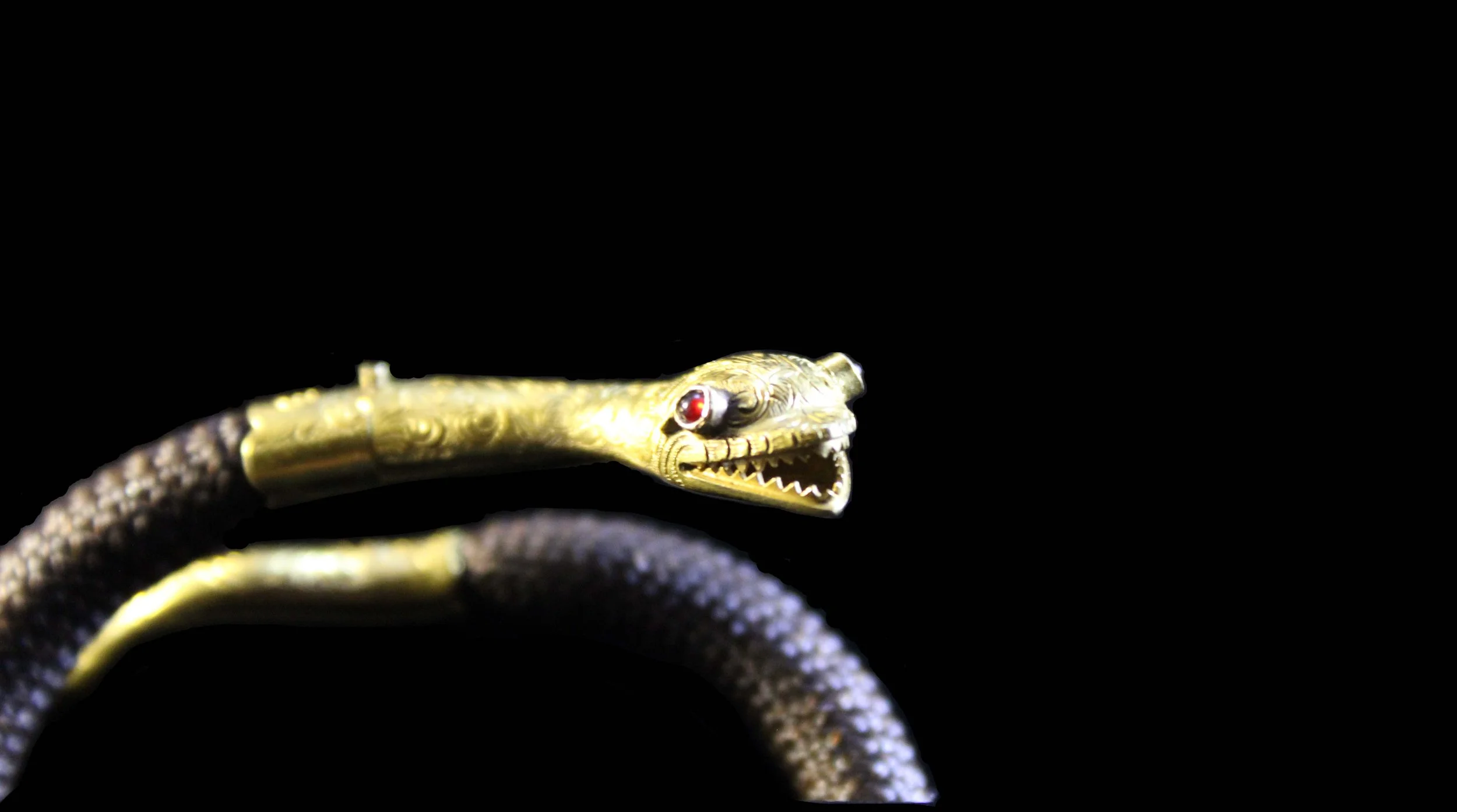 Detail of woven human hair bracelet joined to engraved 18K gold serpent collar