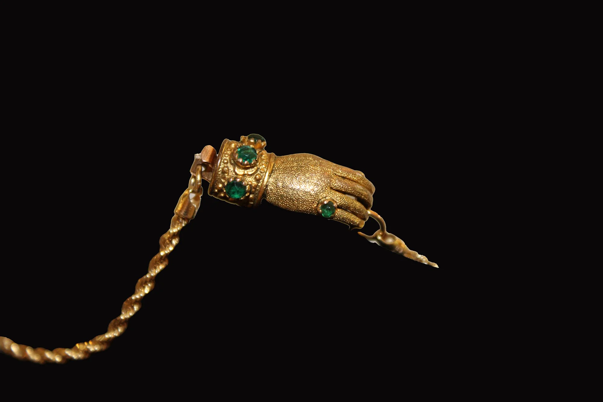 Close-up of Victorian hand clasp bracelet showing textured gold hand and green cabochon-set cuff.