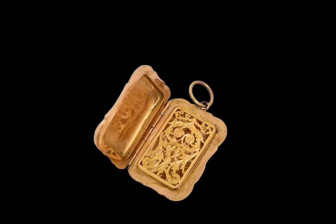 Open antique Swiss gold vinaigrette showing hinged case and finely pierced foliate gold grille with scrolling floral ornament.