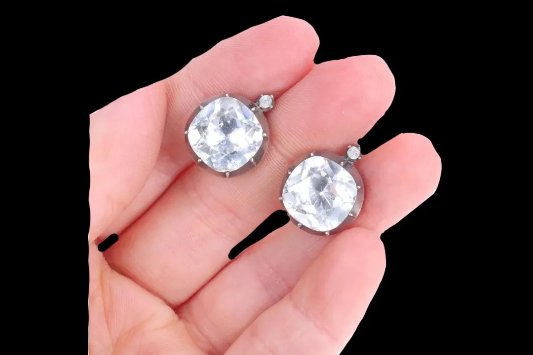 Georgian foil-back paste earrings resting on fingertips, showing their 18.5 mm length and brilliant round faceted glass stones.
