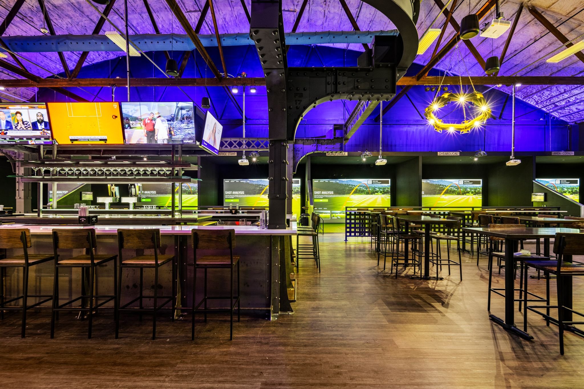 Spacious bar and dining area at Back 9 Social Wallingford CT, with Trackman golf simulator bays and large screens visible in the industrial-style venue