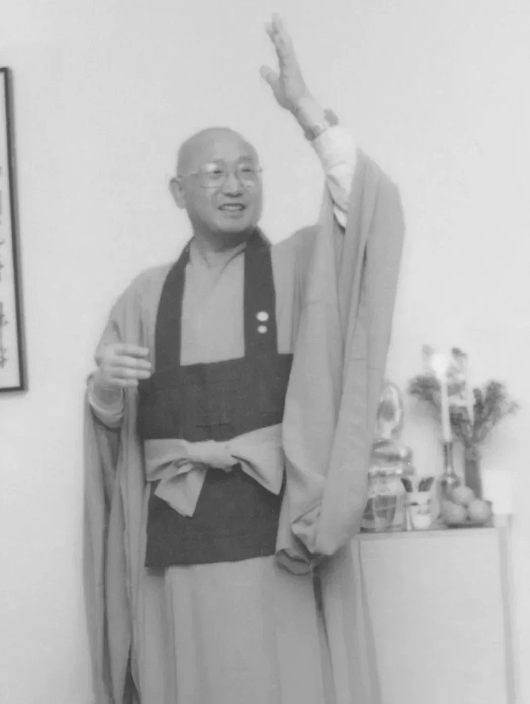 Zen Master Seung Sahn in Korean Zen robes, arm raised, speaking at the dedication ceremony for 400 East 14th Street, 1987. Ceremonial objects are visible on a table behind him.