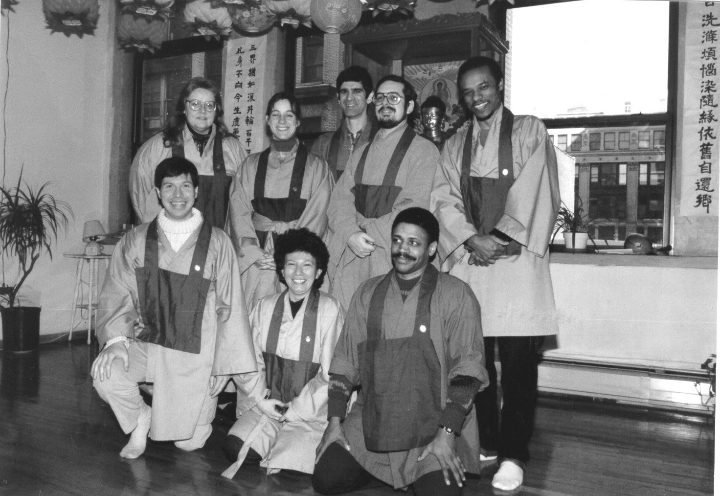 Group photo of Chogye International Zen Center practitioners in the dharma room at 42 West 17th Street, circa 1985. Several members wear traditional Korean Zen practice robes. Korean calligraphy and decorative lanterns are visible in the background.