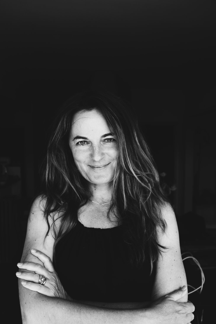 Black and white portrait of a founder Carmen Sosich with long hair smiling, arms crossed.