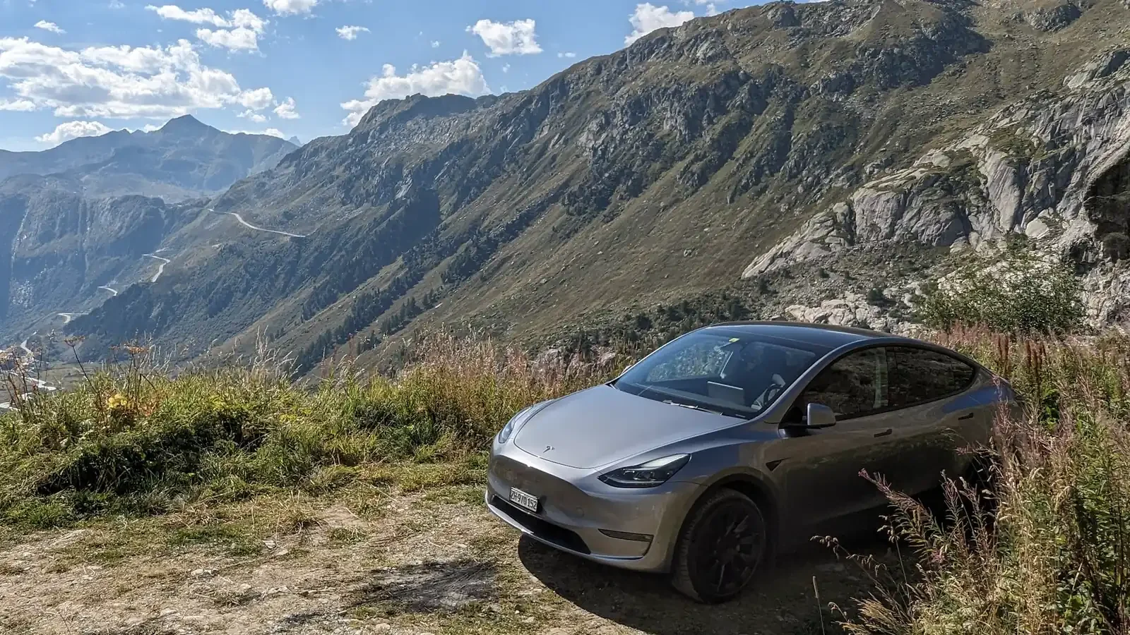 Grauer Tesla Model Y von EV-Adventure auf einer Passstrasse in den Schweizer Alpen