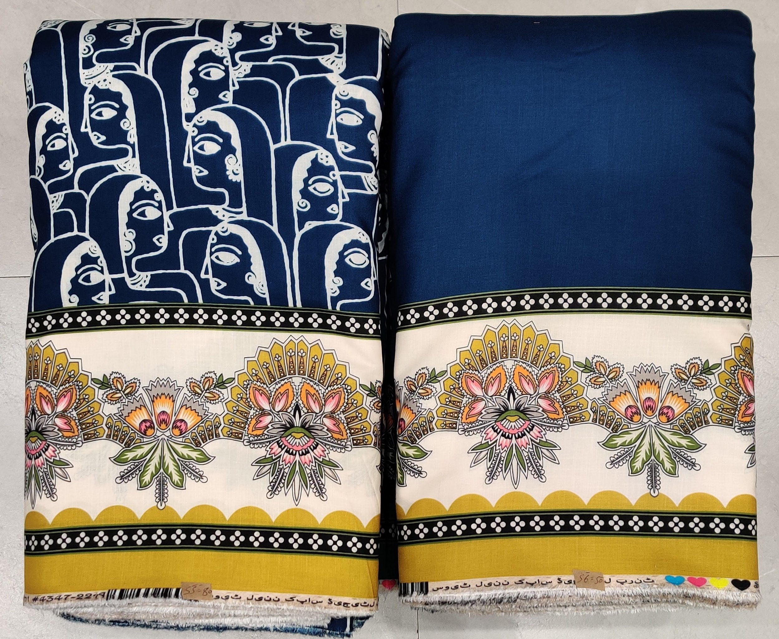 Rich royal-blue and crisp ivory fabric featuring an artistic panel print of traditional stylized faces on the left, paired with an intricate geometric border and a vibrant patterned hemline along the right.