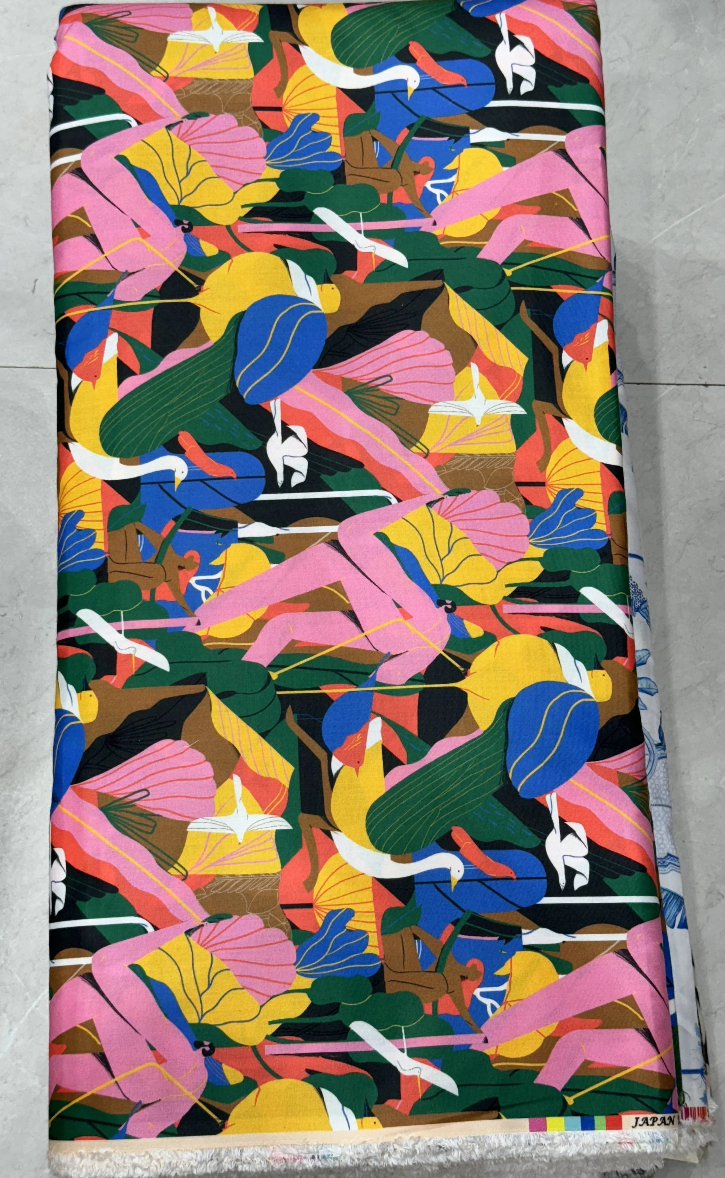 Vibrant multi-colored fabric featuring an energetic abstract mosaic design with bold geometric blocks in rich red, orange, blue, green, and purple tones.