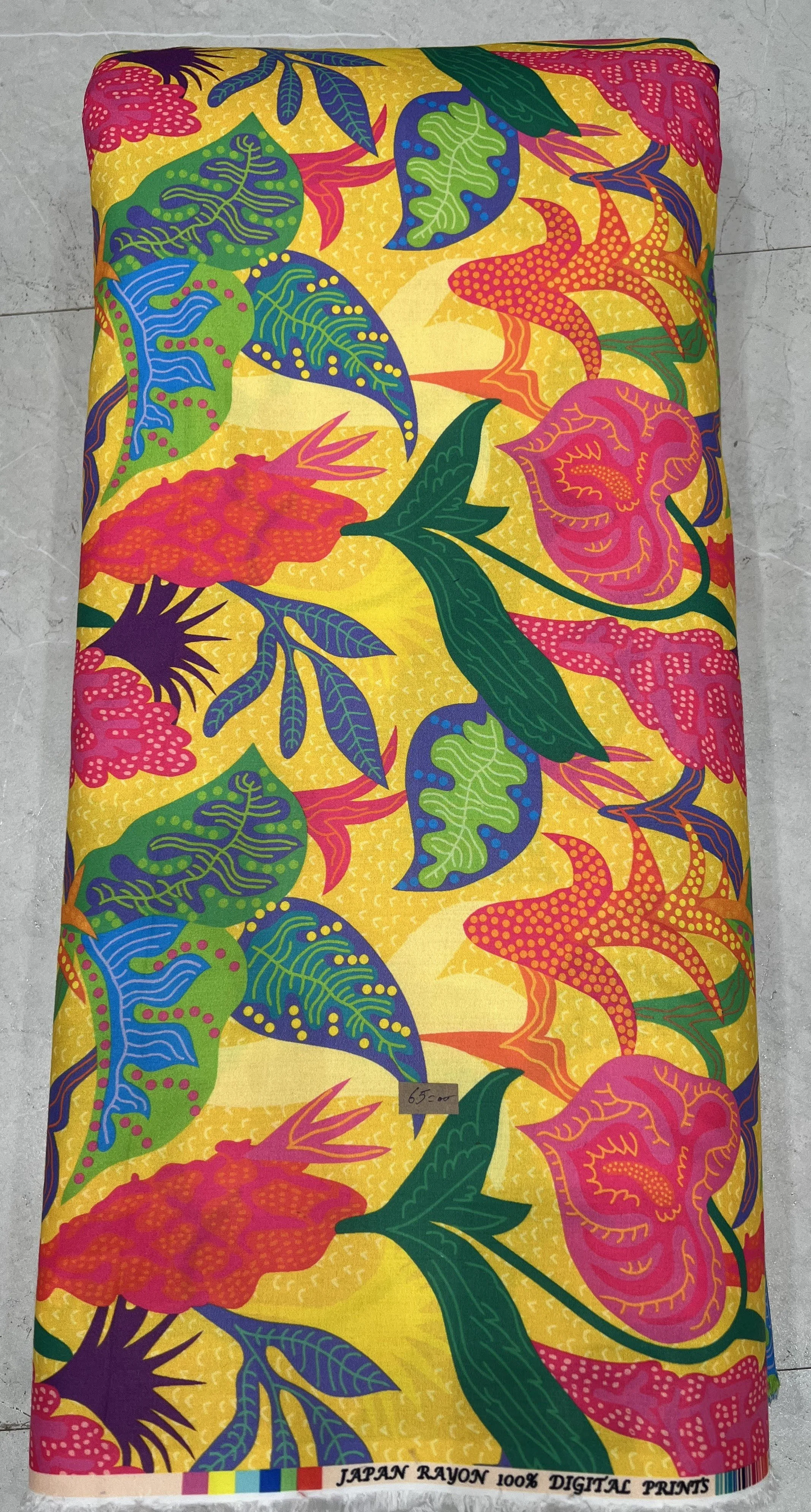 Rich golden-yellow fabric featuring a scattered botanical print with large, vibrant pink and magenta floral blossoms and dark green foliage.