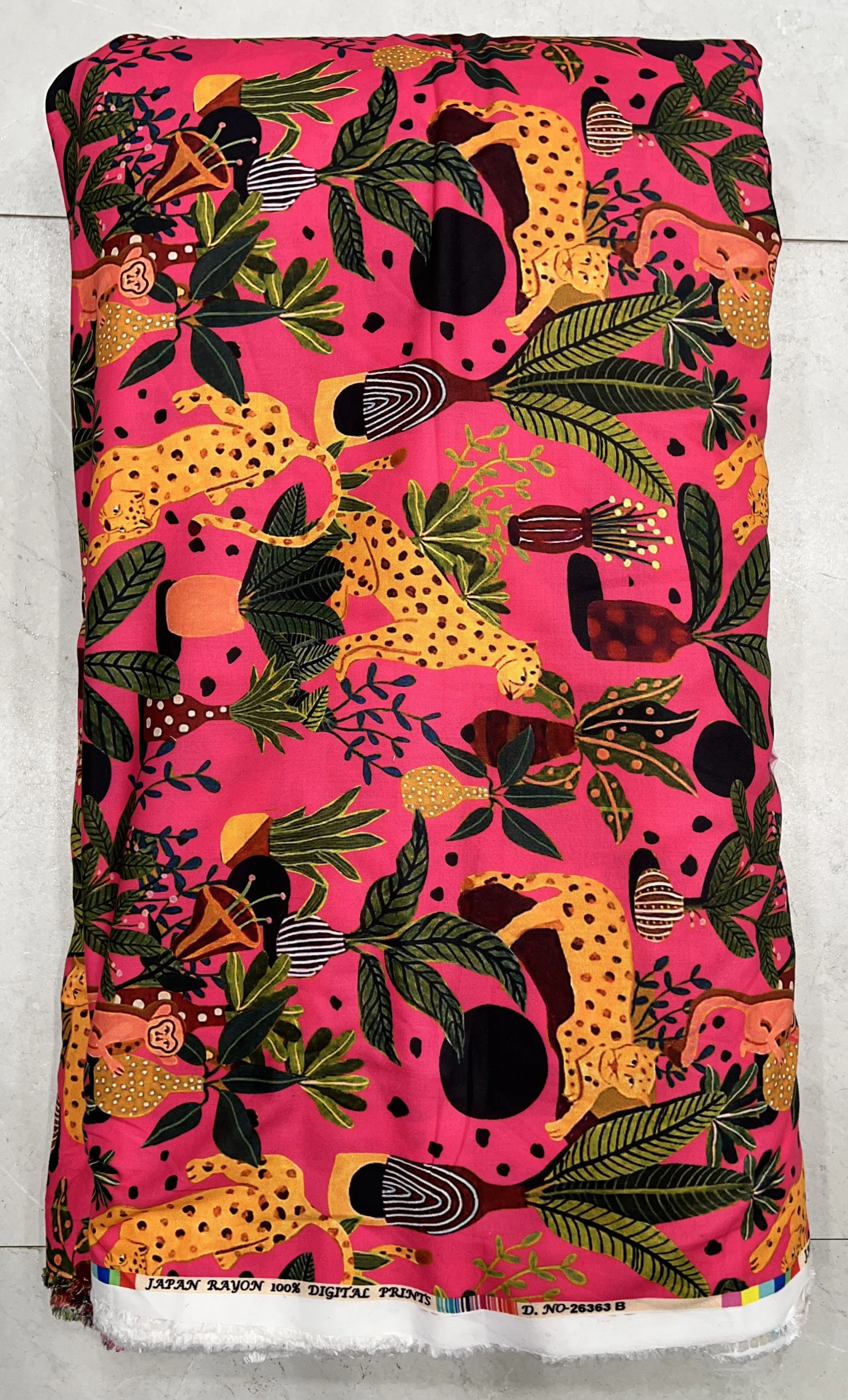 Vibrant pink fabric featuring a lively tropical print with playful monkeys, exotic birds, and colorful botanical foliage.