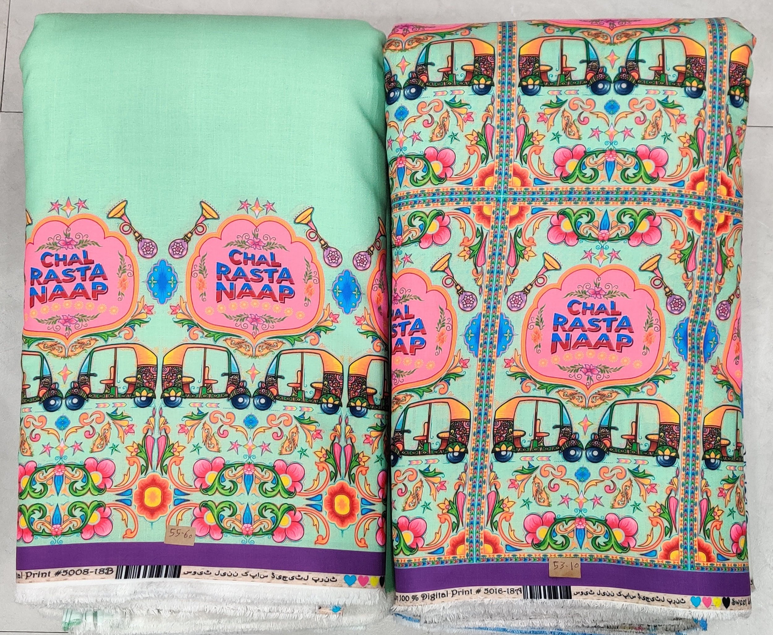 Vibrant turquoise and pink fabric featuring a whimsical street scene print with colorful auto-rickshaws, traditional motifs, and decorative borders.