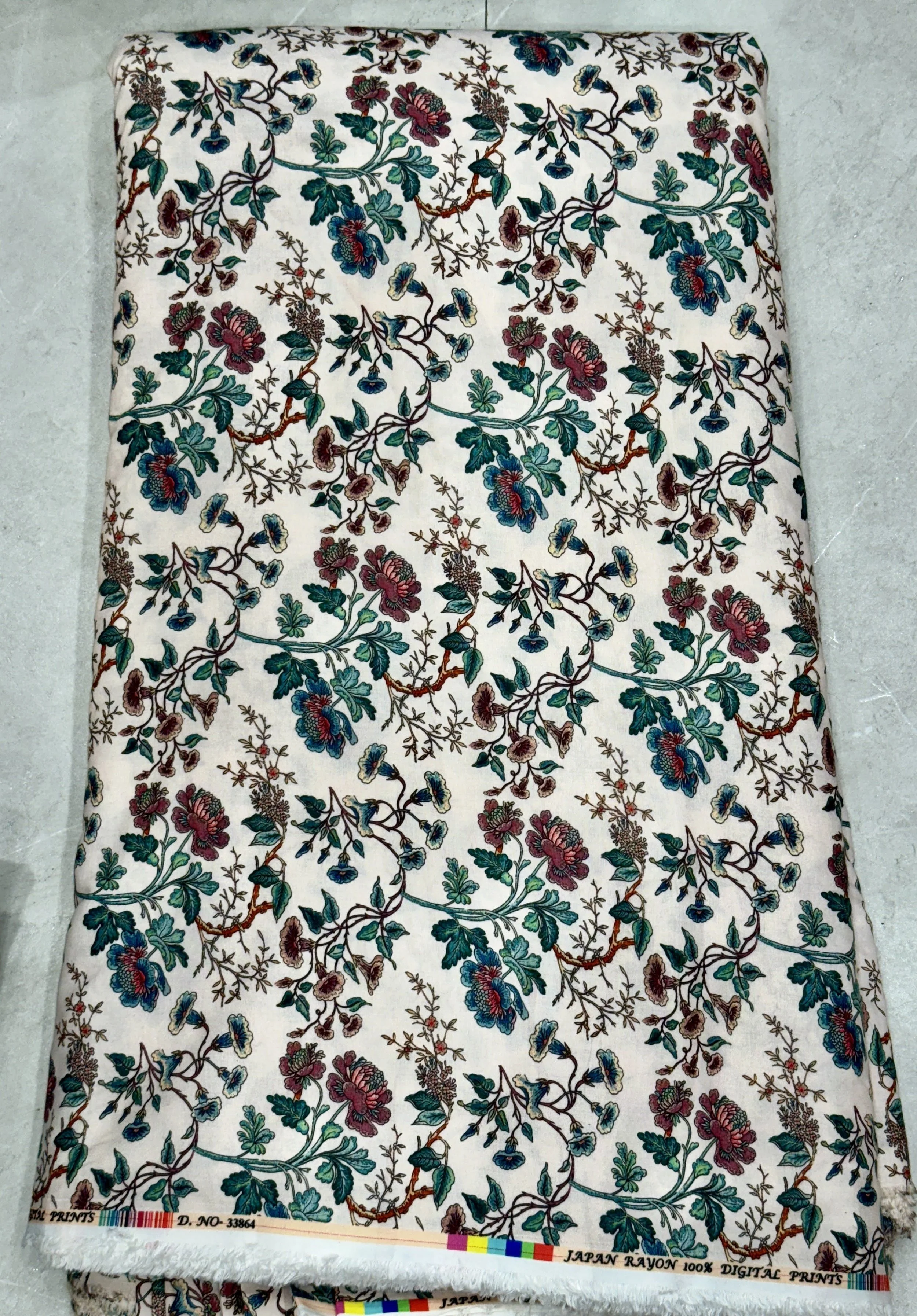 Soft white fabric featuring a dense floral pattern with delicate dark red, green, and navy blossoms cascading across the surface.