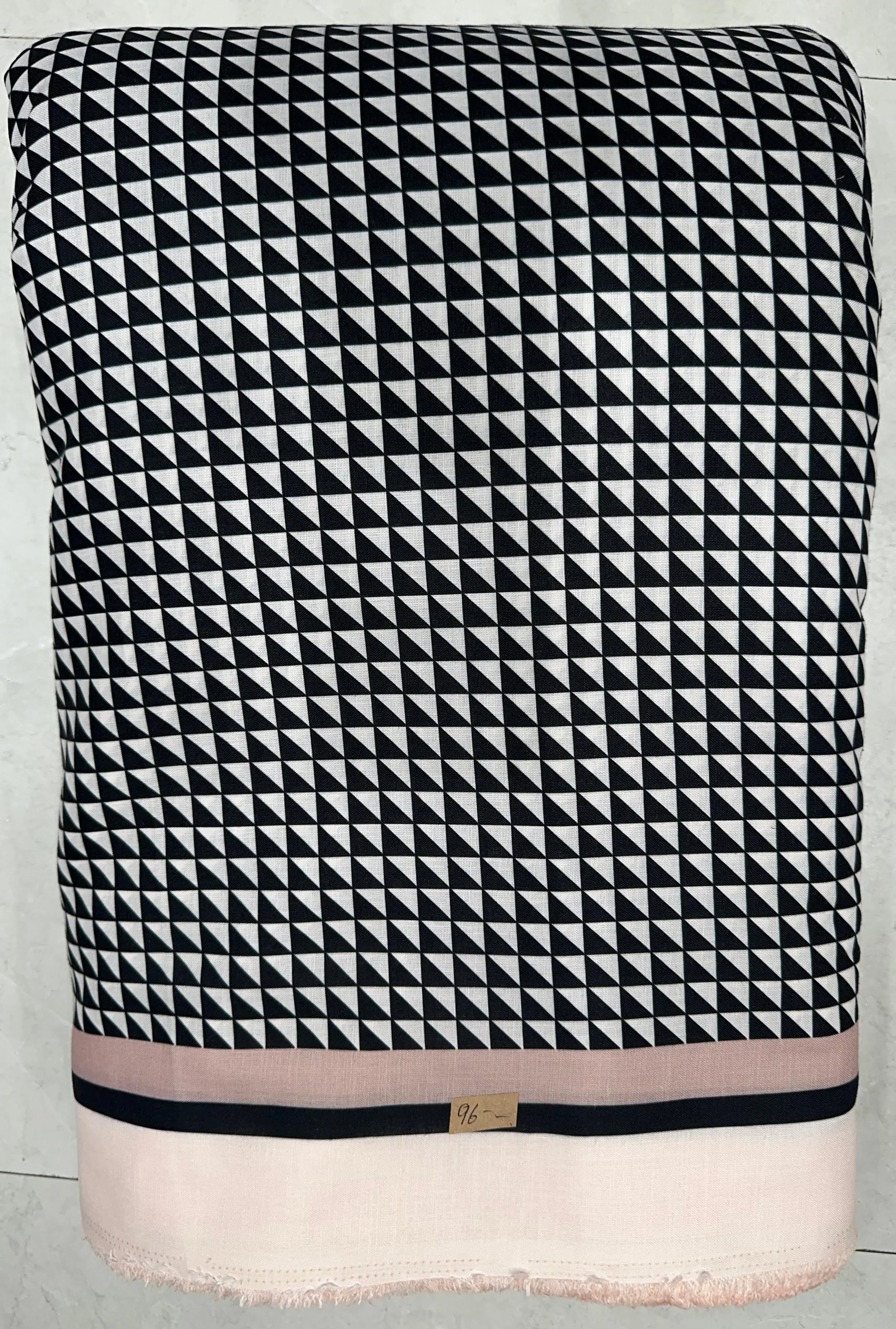 Structured monochrome and soft blush-pink fabric featuring an all-over geometric triangle pattern, finished with a delicate contrasting pastel border.