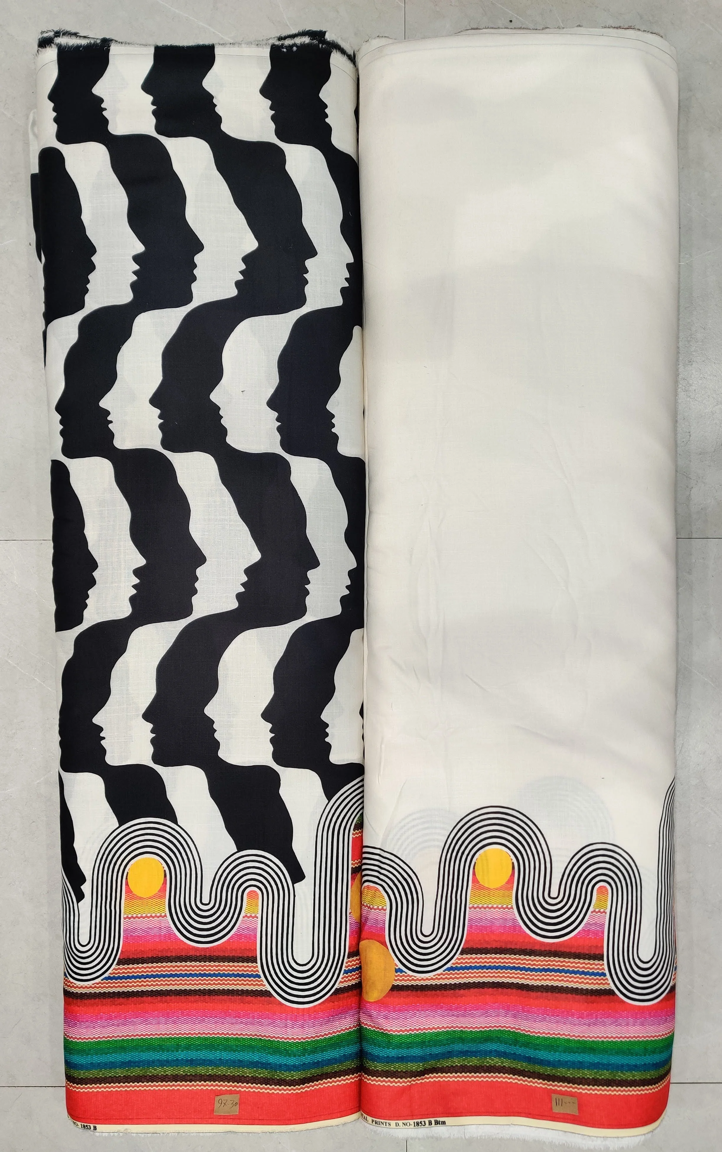 Classic black-and-white fabric featuring a bold chevron-stripe pattern on the left panel, paired with a solid white right panel, and a colorful multi-striped hemline border.
