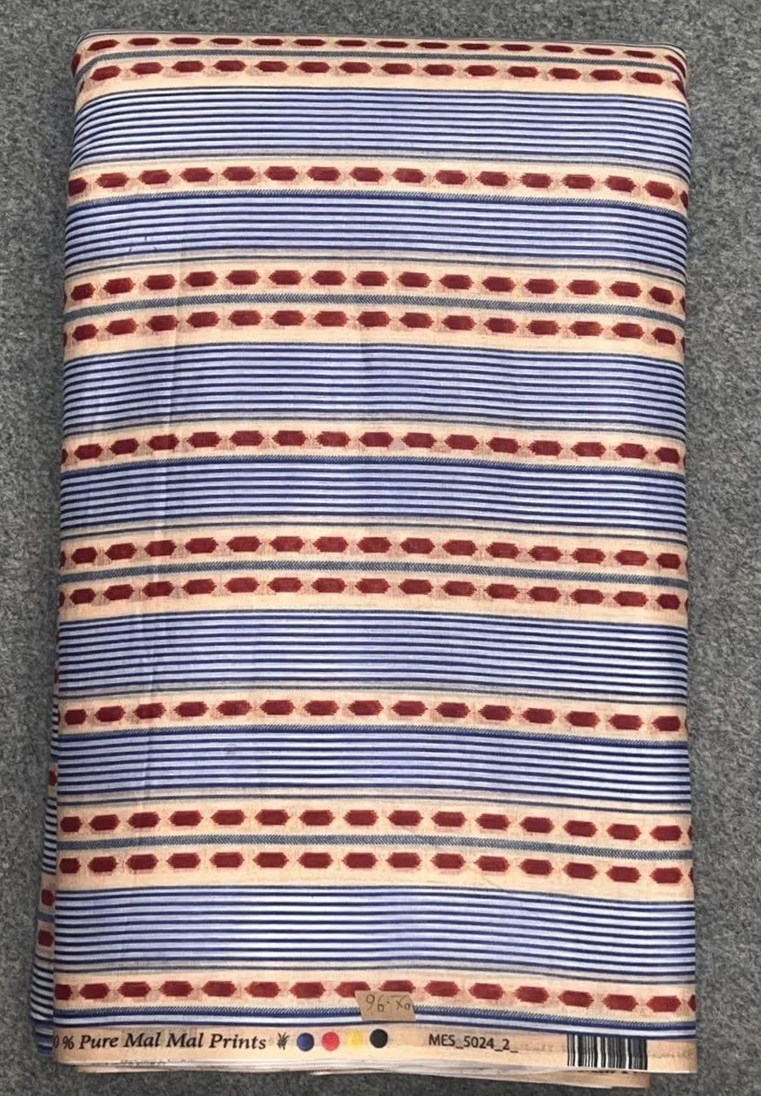 A fabric sample with red, white, blue, and black horizontal stripe patterns, labeled as 96% pure Mal Mal prints, lying on a gray textured surface.