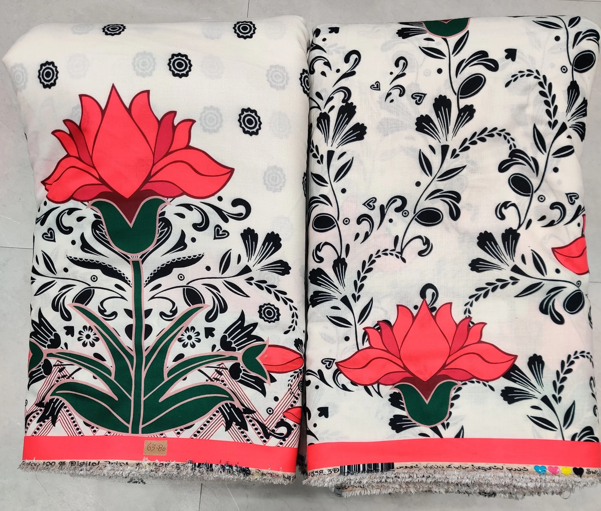 Crisp white and jet-black border-print fabric featuring a bold red lotus medallion motif on the left panel, paired with intricate floral vines and a matching red-striped hemline band on the right.