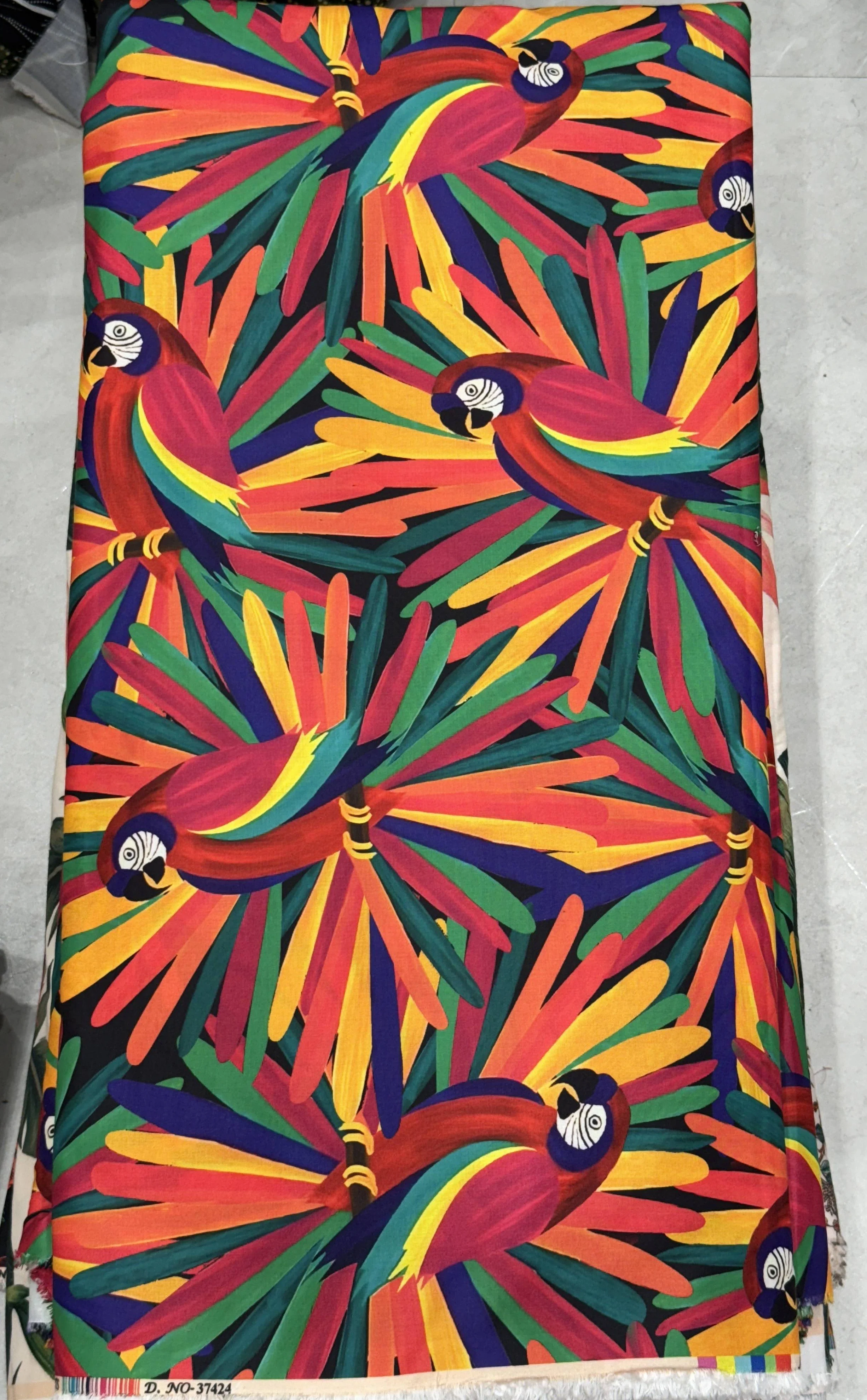 Vibrant multi-colored fabric featuring a dynamic, sunburst-like pattern filled with intricate multi-hued leaf and feather motifs in rich red, blue, green, and gold tones.