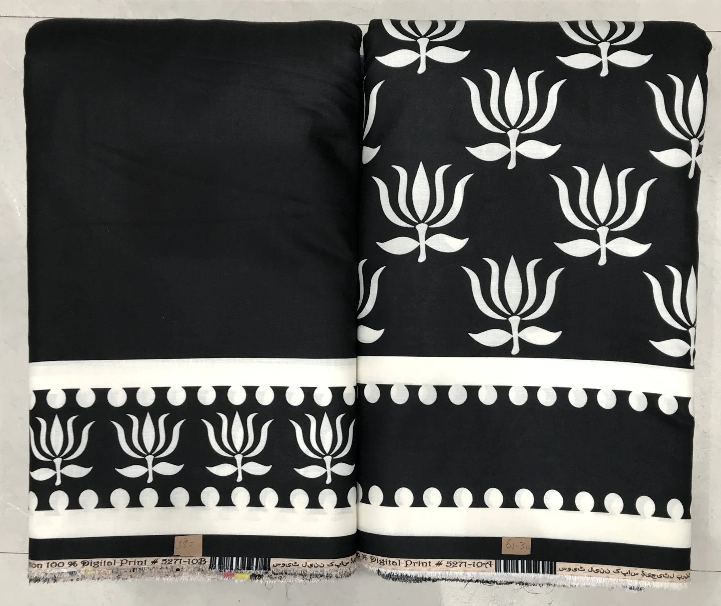 Classic jet-black and pristine ivory border-print fabric featuring a solid black left panel, traditional tulip-motif printed panel on the right, and a structured geometric hemline border.