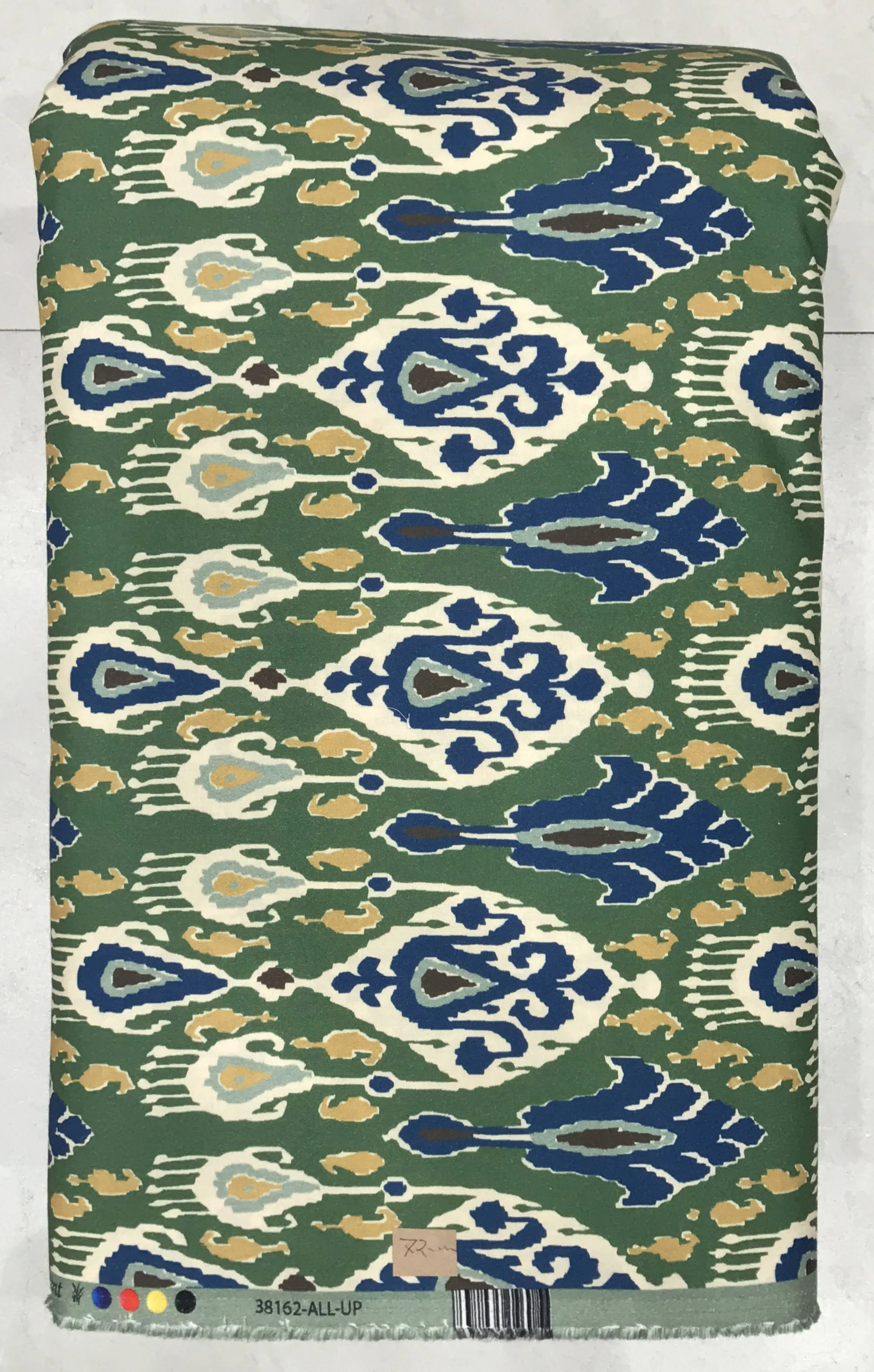 Rich deep green background featuring an intricate, traditional ikat-style pattern with ornate white and soft blue medallion motifs interwoven with delicate floral details.