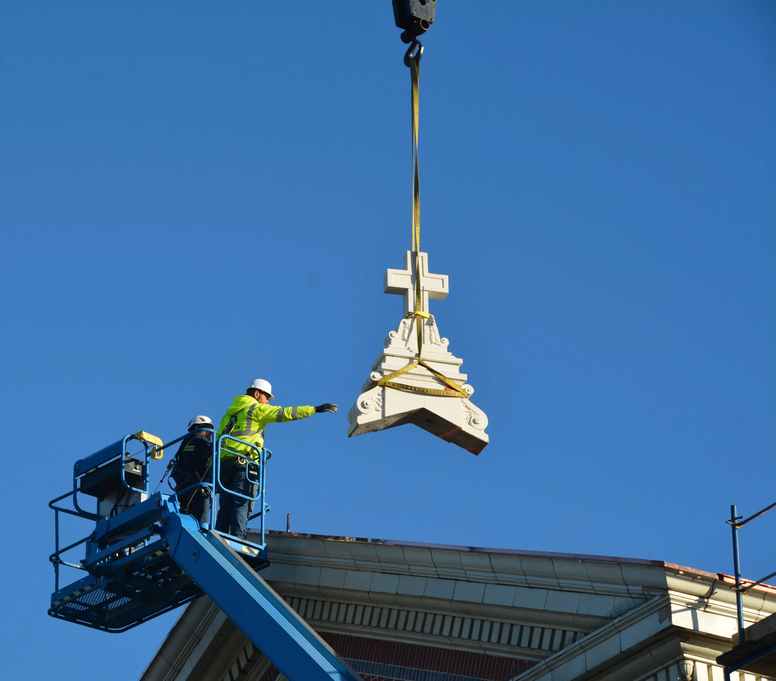 Workman guides Cross into place on roof of Church