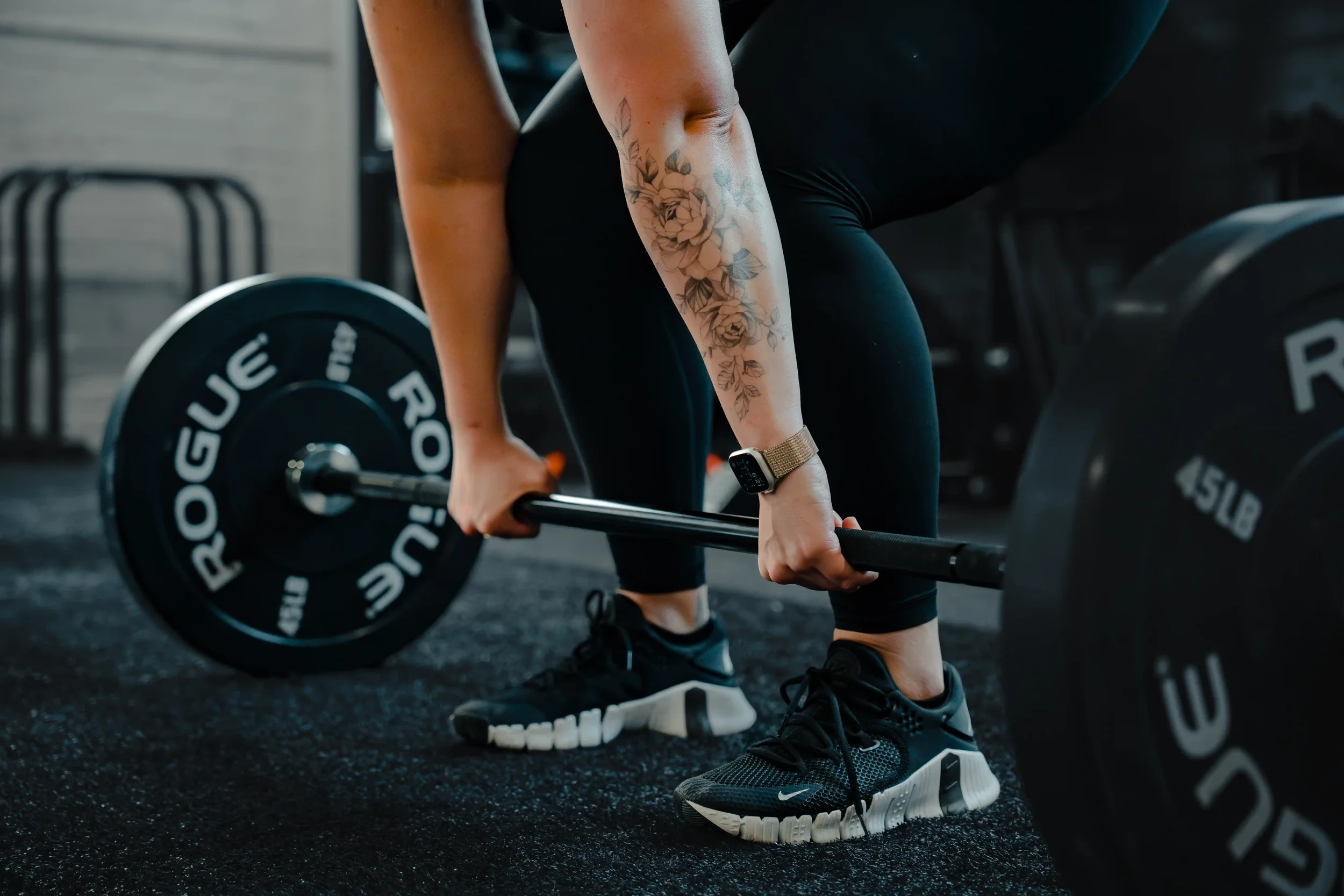 Hands wrapped around a barbell with 45LB plates on either side.