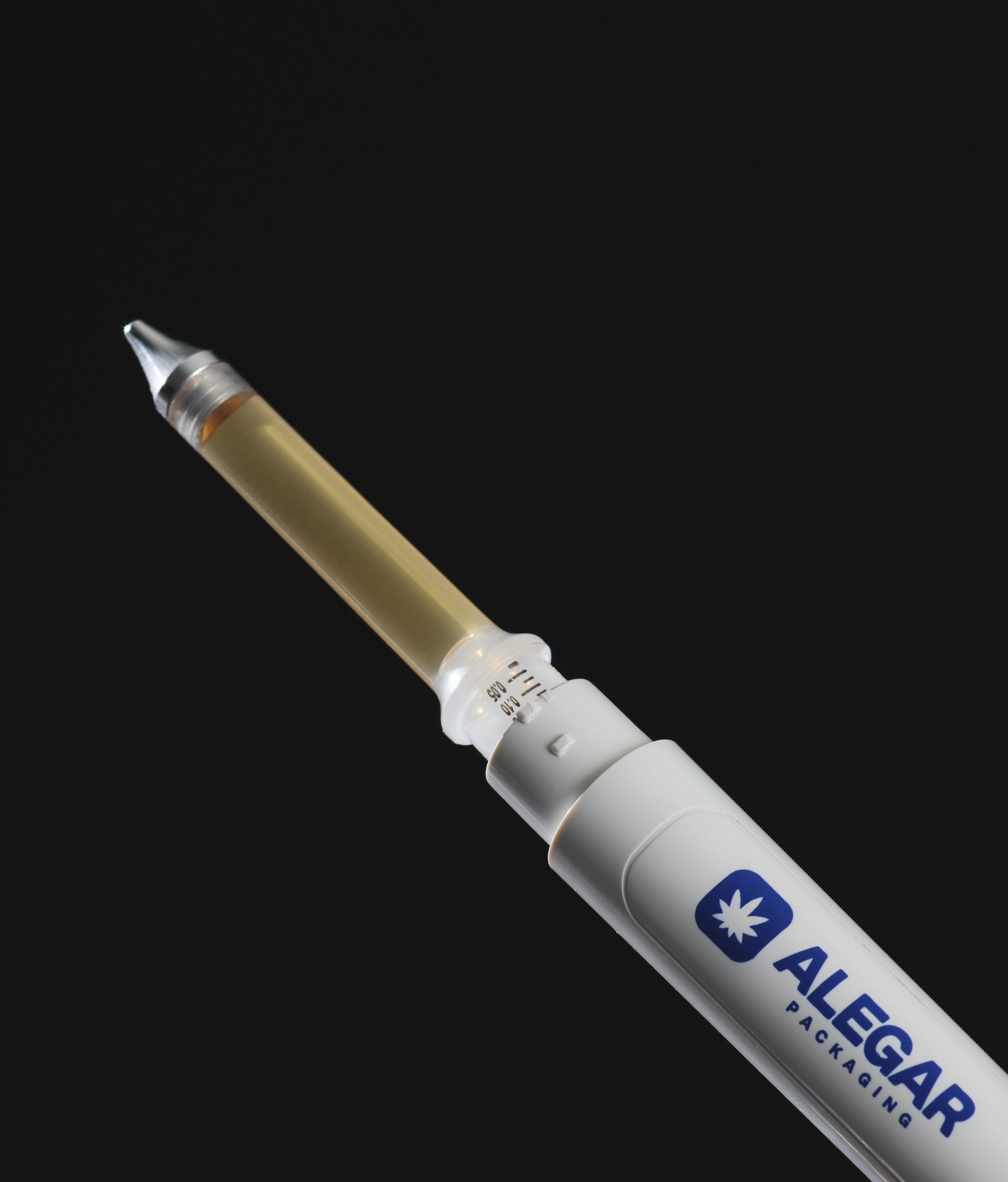 A syringe filled with a clear liquid in front of a black background, with part of a white and blue medical packaging label visible.