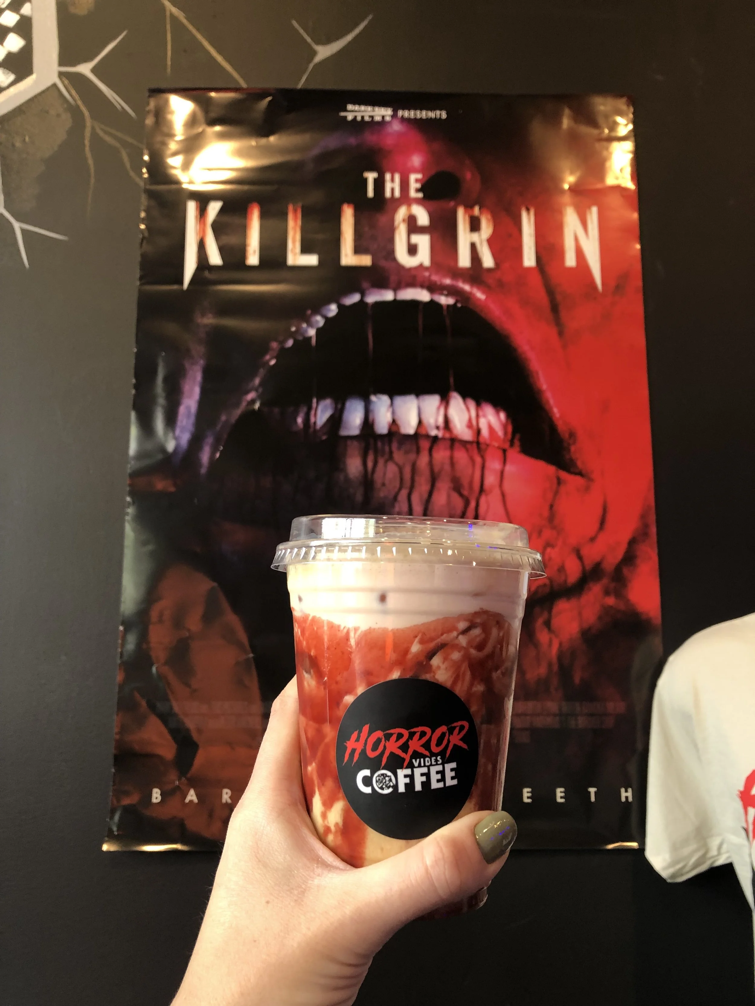 A delicious iced latte posed in front of a movie poster for The Killgrin at Horror Vibes Coffee in North Hollywood, CA