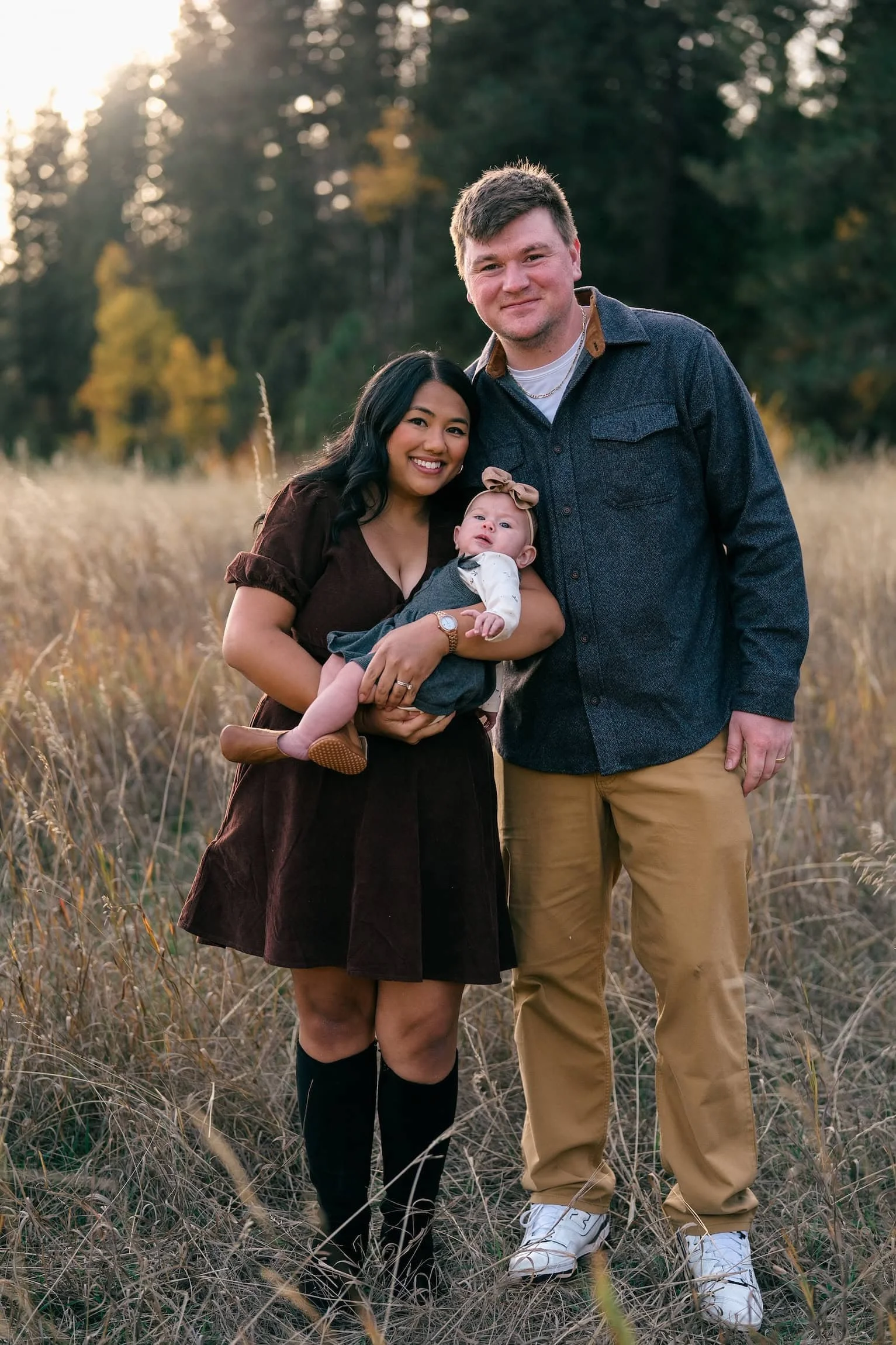 mom and dad with a young baby posing for a professional family photo with fall colors