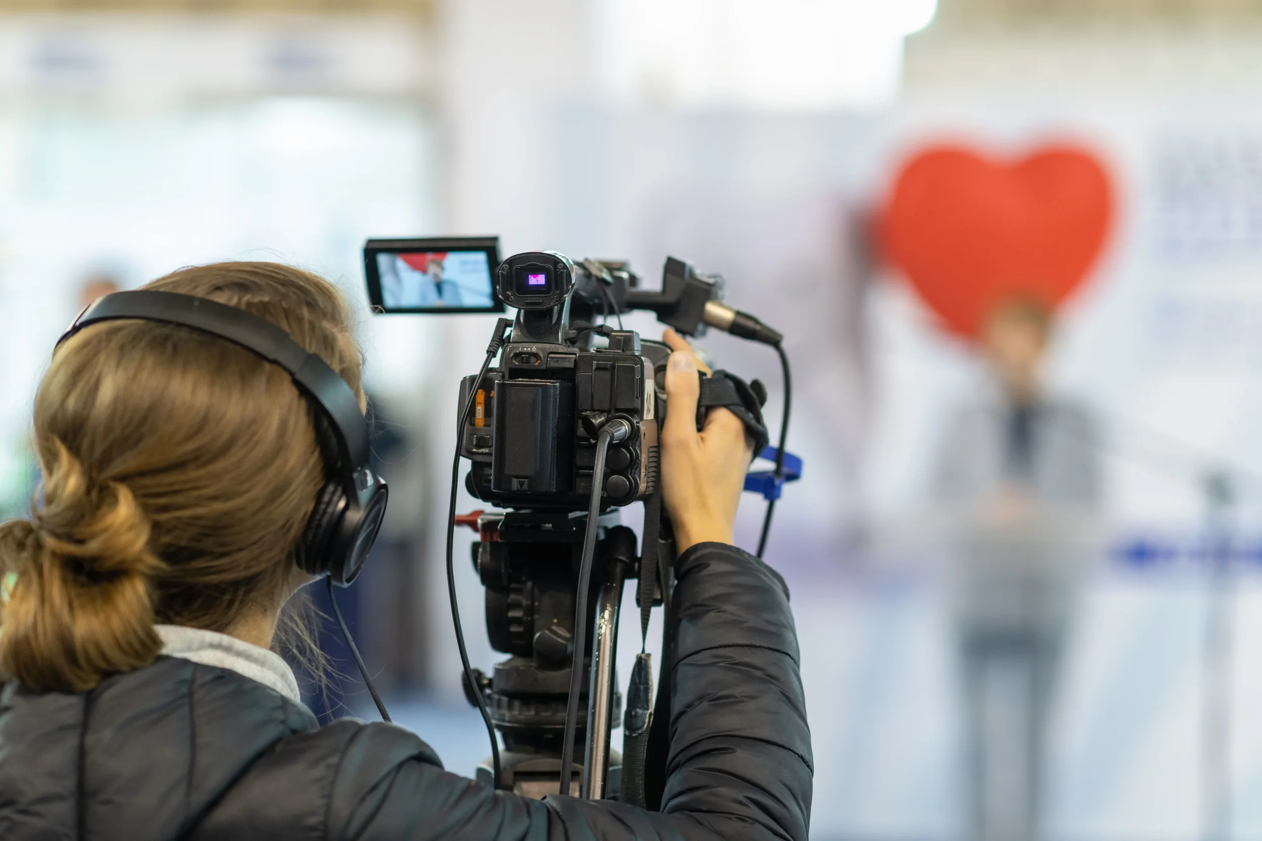 Female videographer with headphones filming a speaker at a health promotion community event