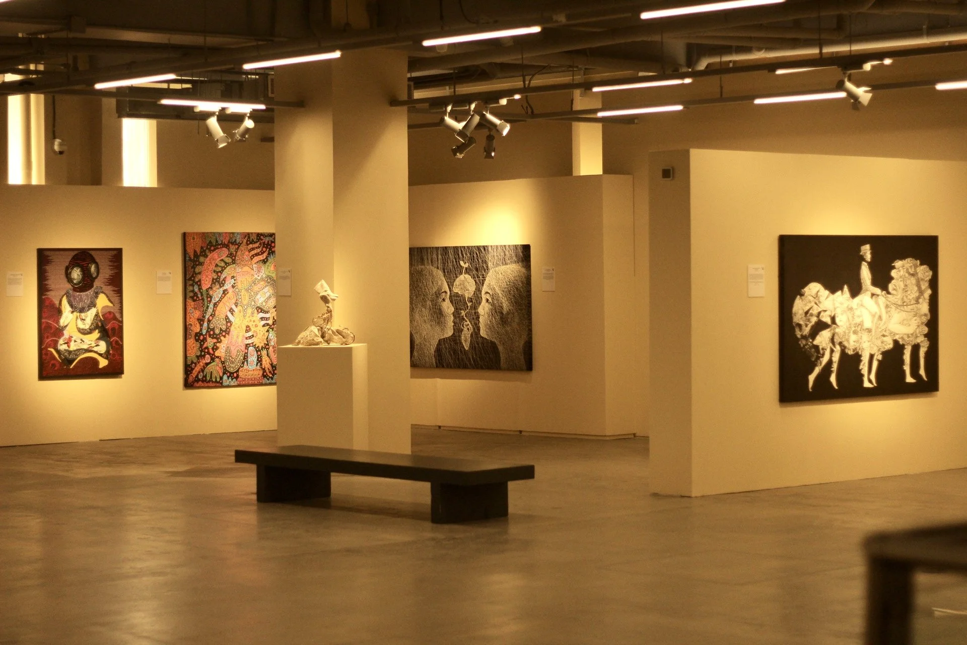 A sculpture of a woman with her arms raised behind her head, displayed in an art gallery.