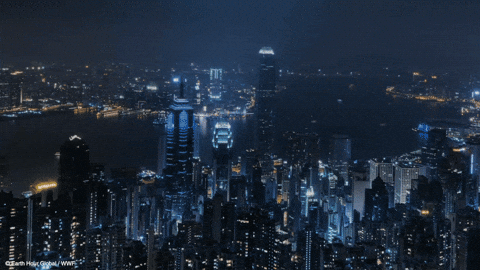 Nighttime aerial view of a illuminated city skyline with tall skyscrapers and a river running through the city.