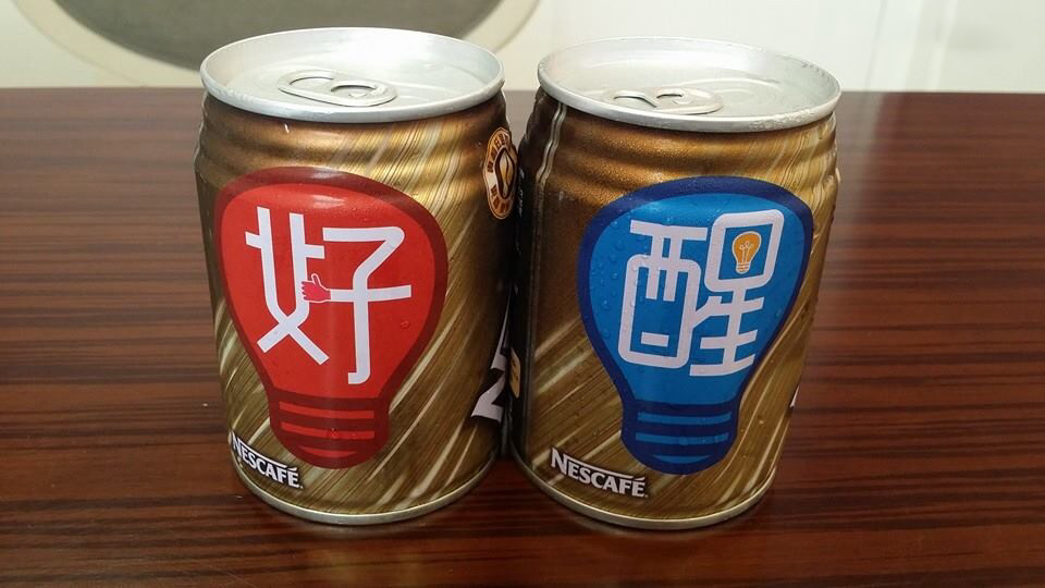 Two cans of Nescafé coffee on a wooden table, one with a red speech bubble and Chinese characters, the other with a blue speech bubble and Chinese characters.