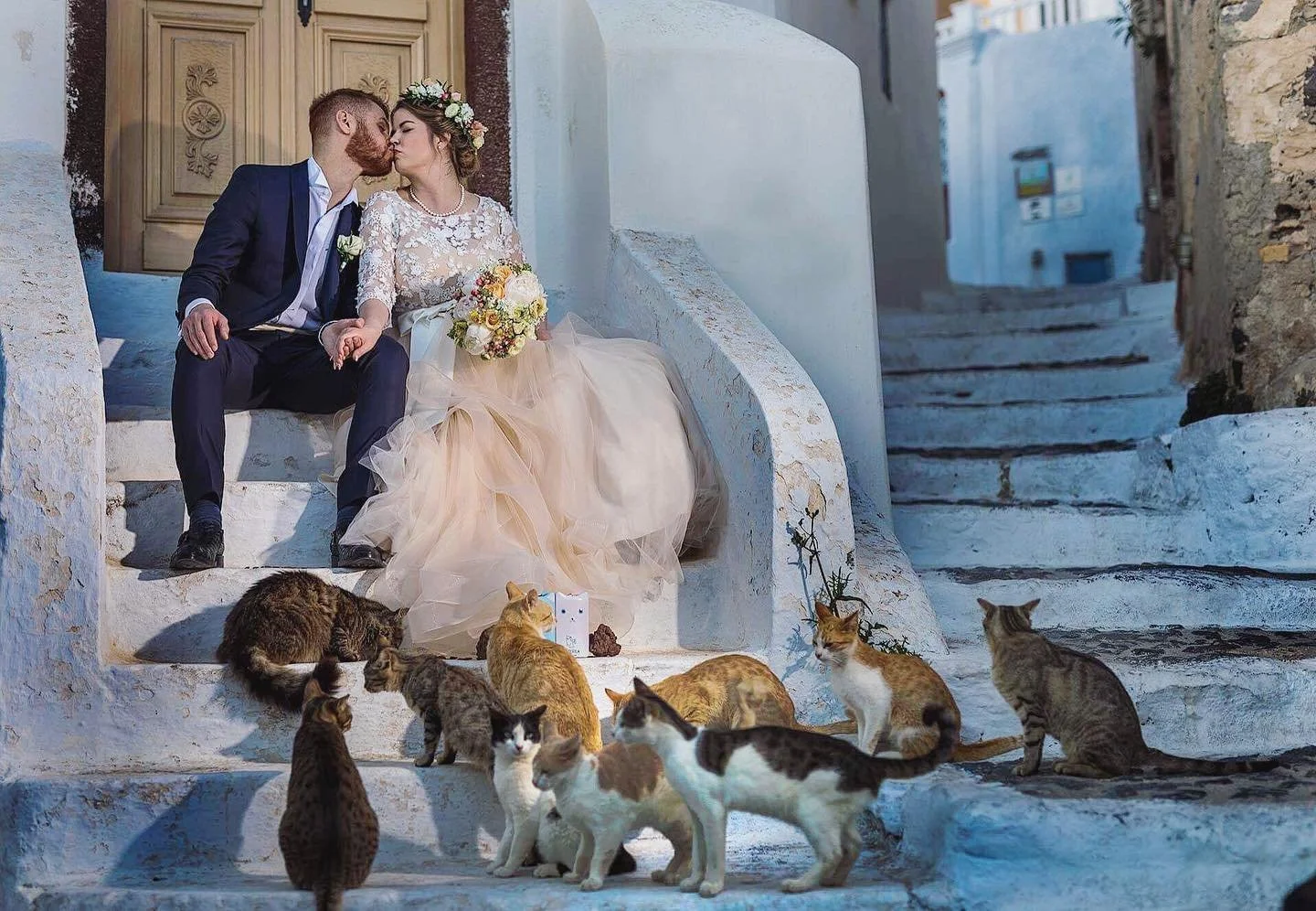 Santorini wedding photography low‑angle reflection shot at Amoudi Bay capturing couple and cliff reflections on calm water during sunrise.