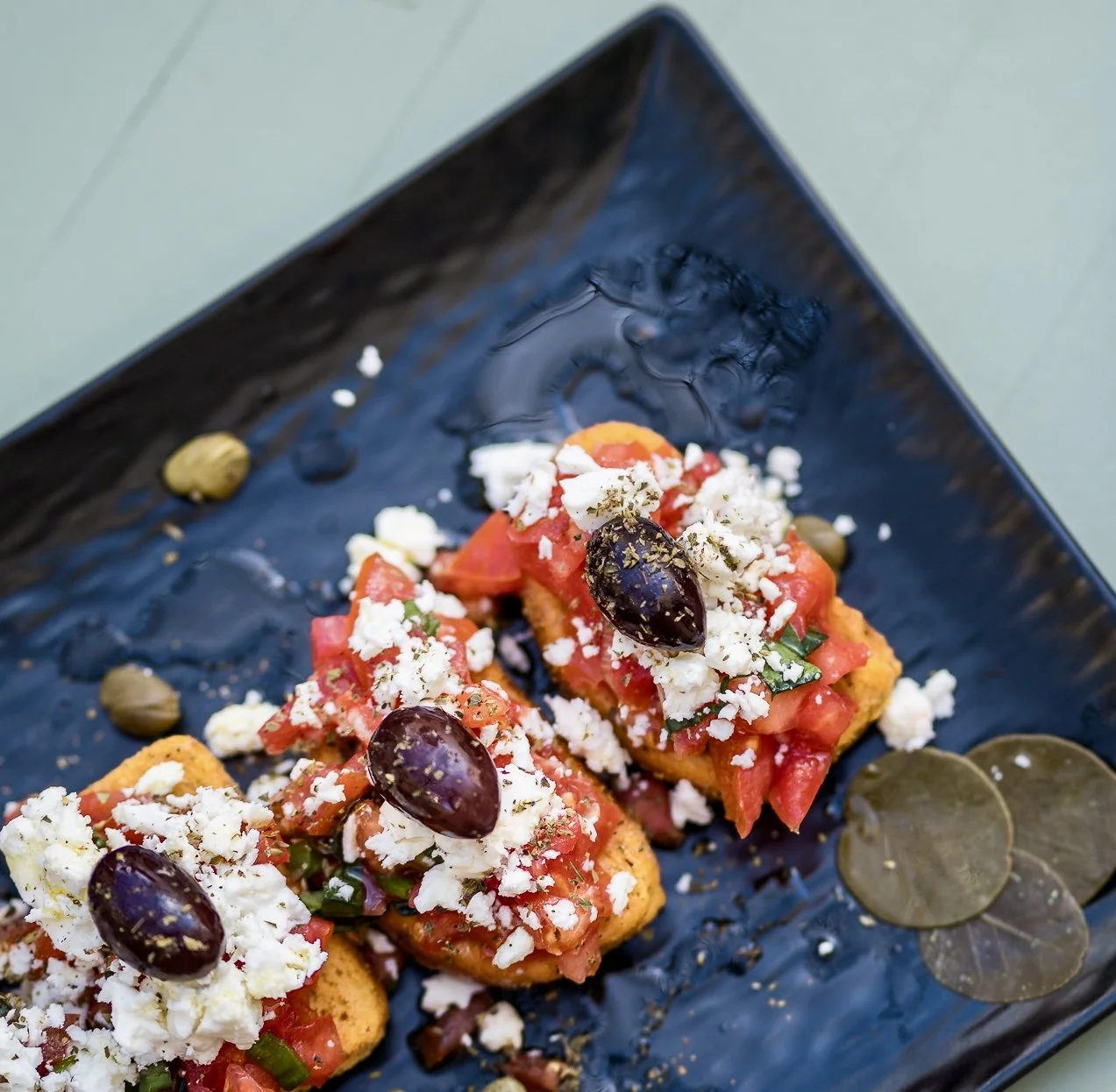 Karma’s Ntakos is a delicious taste of Crete—crisp barley rusk topped with juicy tomatoes, creamy local cheese, fragrant herbs, and a drizzle of extra virgin olive oil. Fresh, rustic, and full of authentic Greek flavor.
