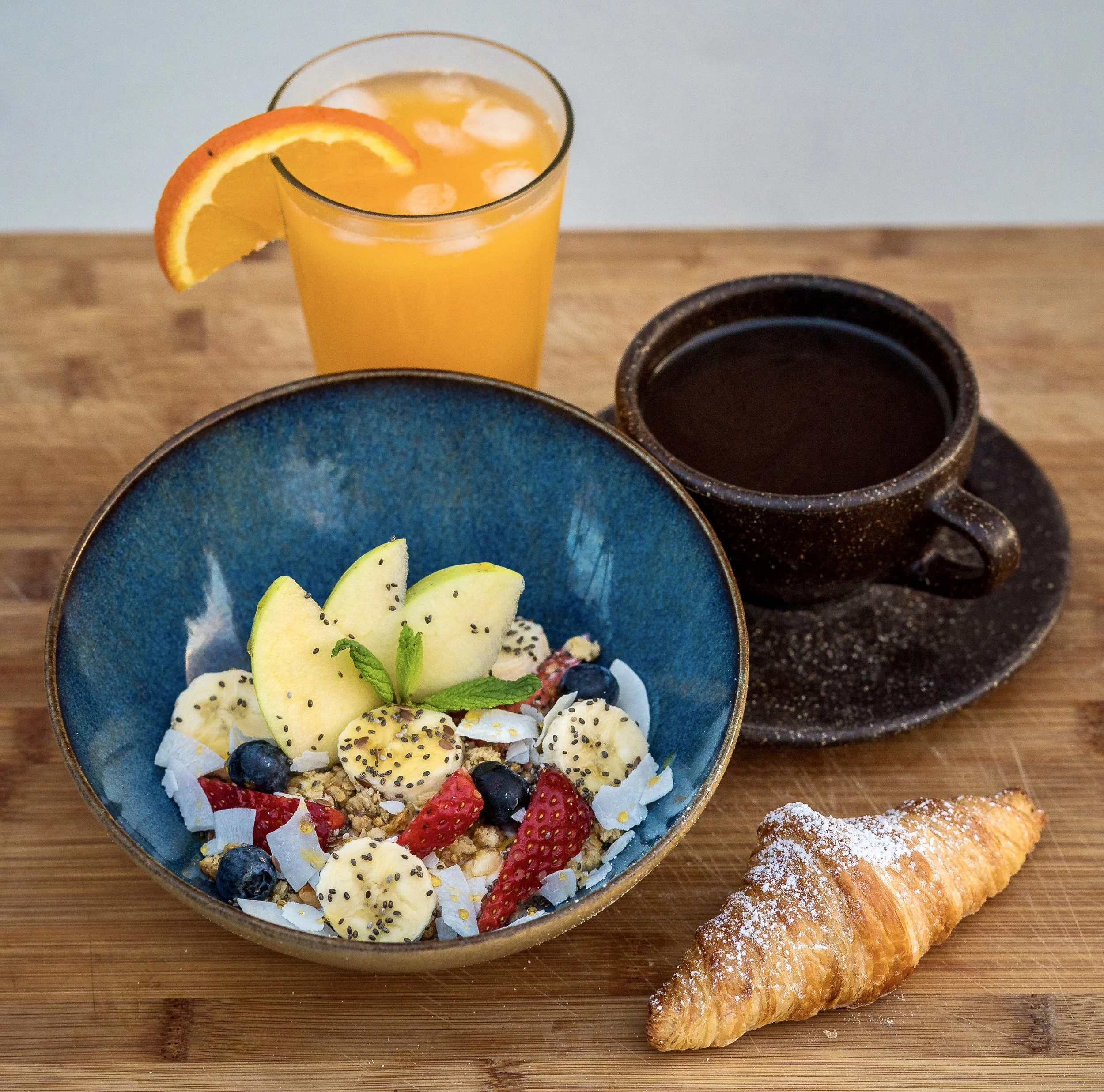 Authentic Greek-inspired breakfast served at Karma Greek Restaurant in Oia, Santorini, including grilled halloumi, beef sausage, sautéed peppers and onions, toasted pita, yogurt, granola, fresh fruit, and Greek honey.